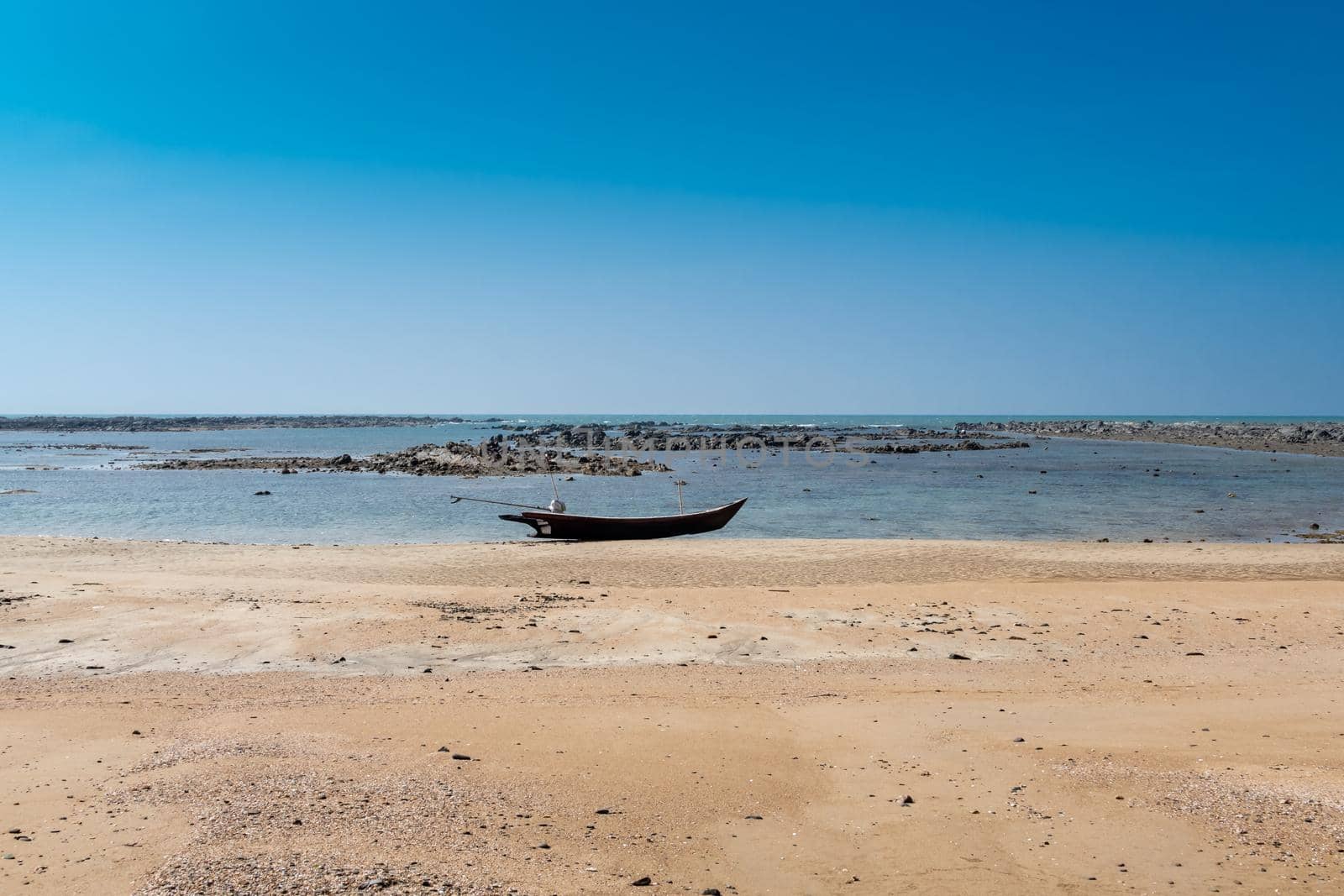 Longboat on beach with rocks in background by imagesbykenny