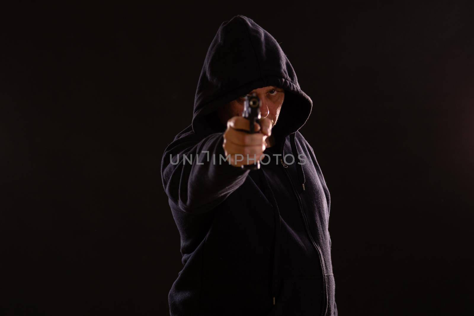 Man in black hoodie points handgun