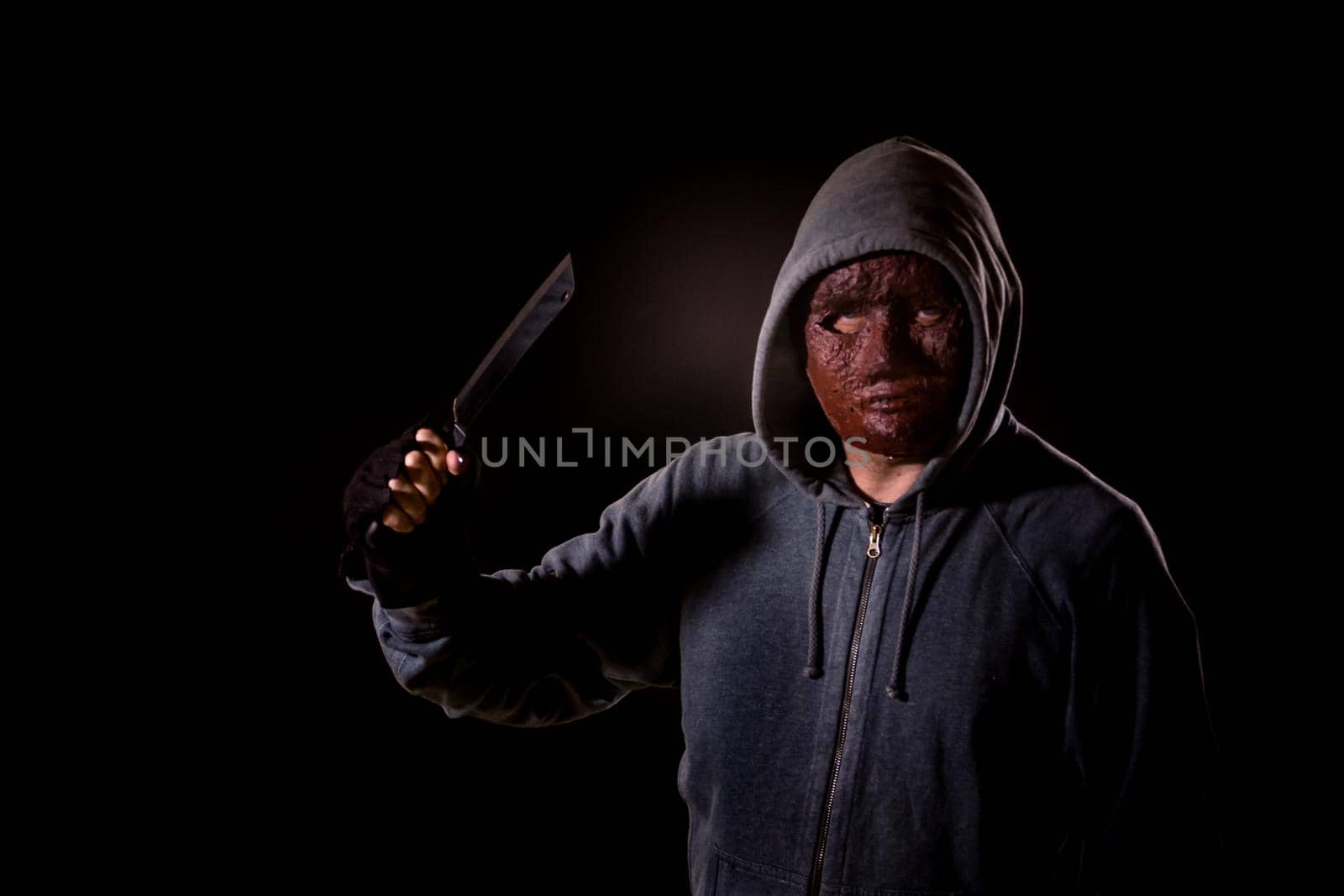 Scary killer in mask and hoodie holding knife