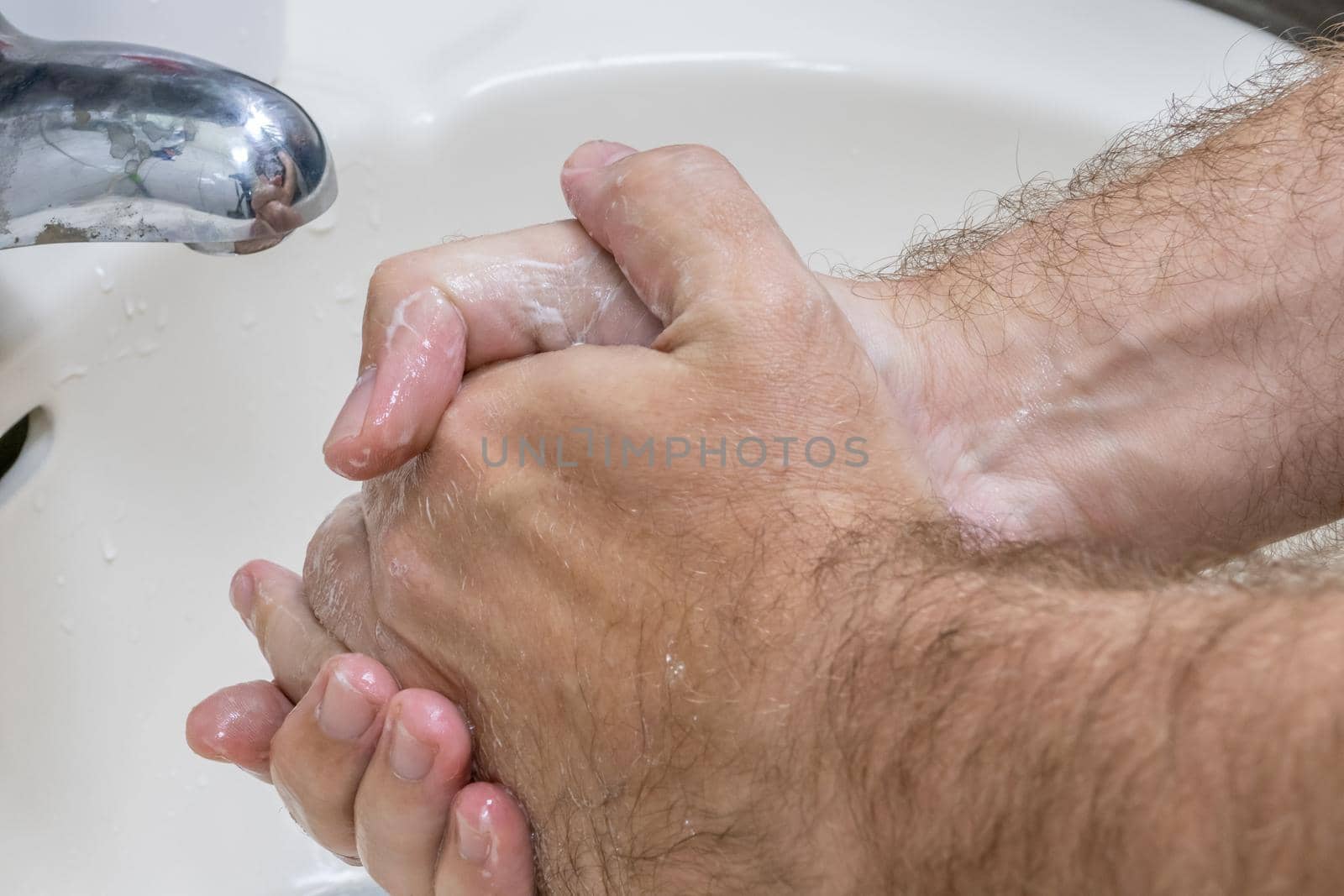 Man washing hands in basin close-up, one of several in handwashing steps series