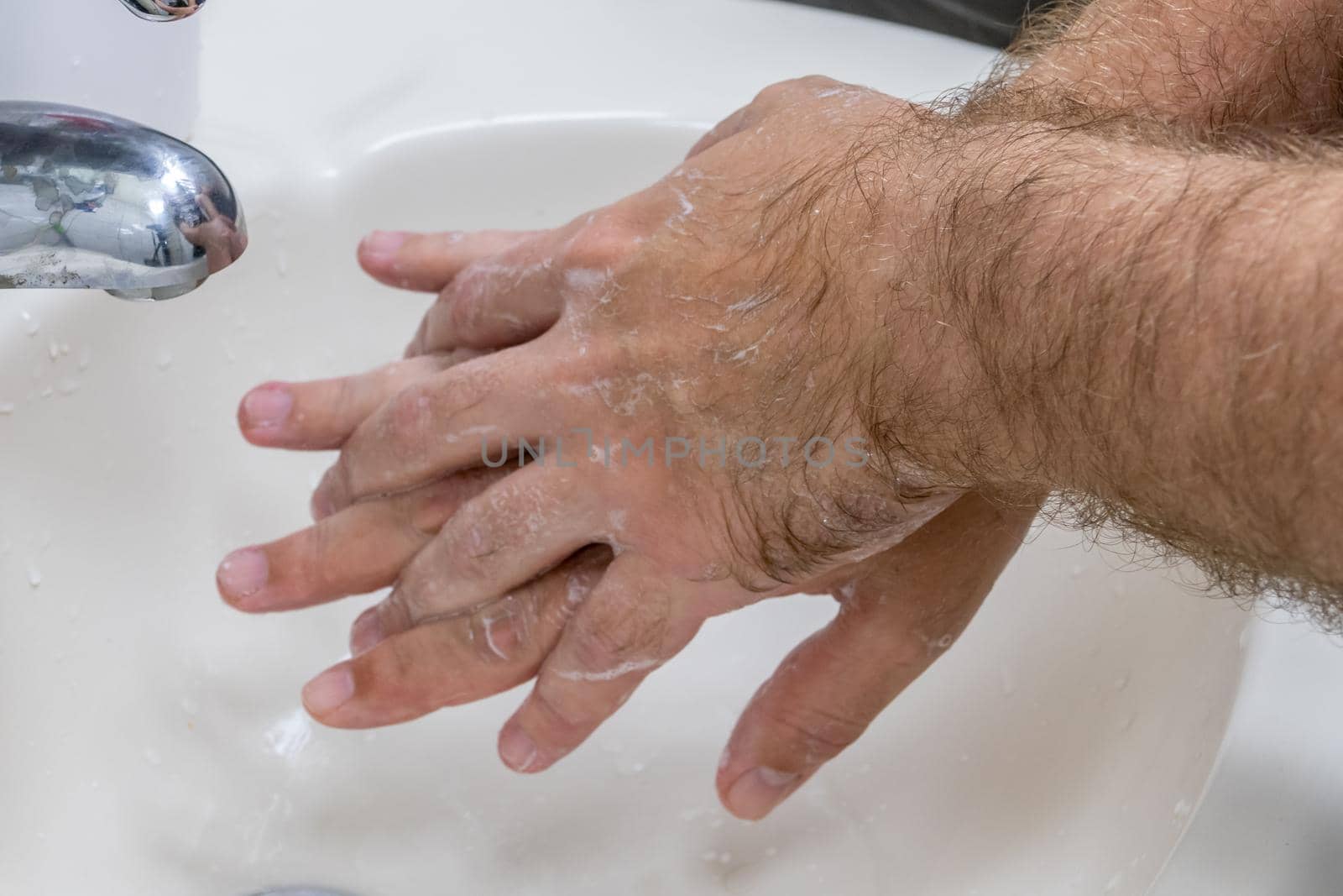 Man washing hands in basin close-up, one of several in handwashing steps series