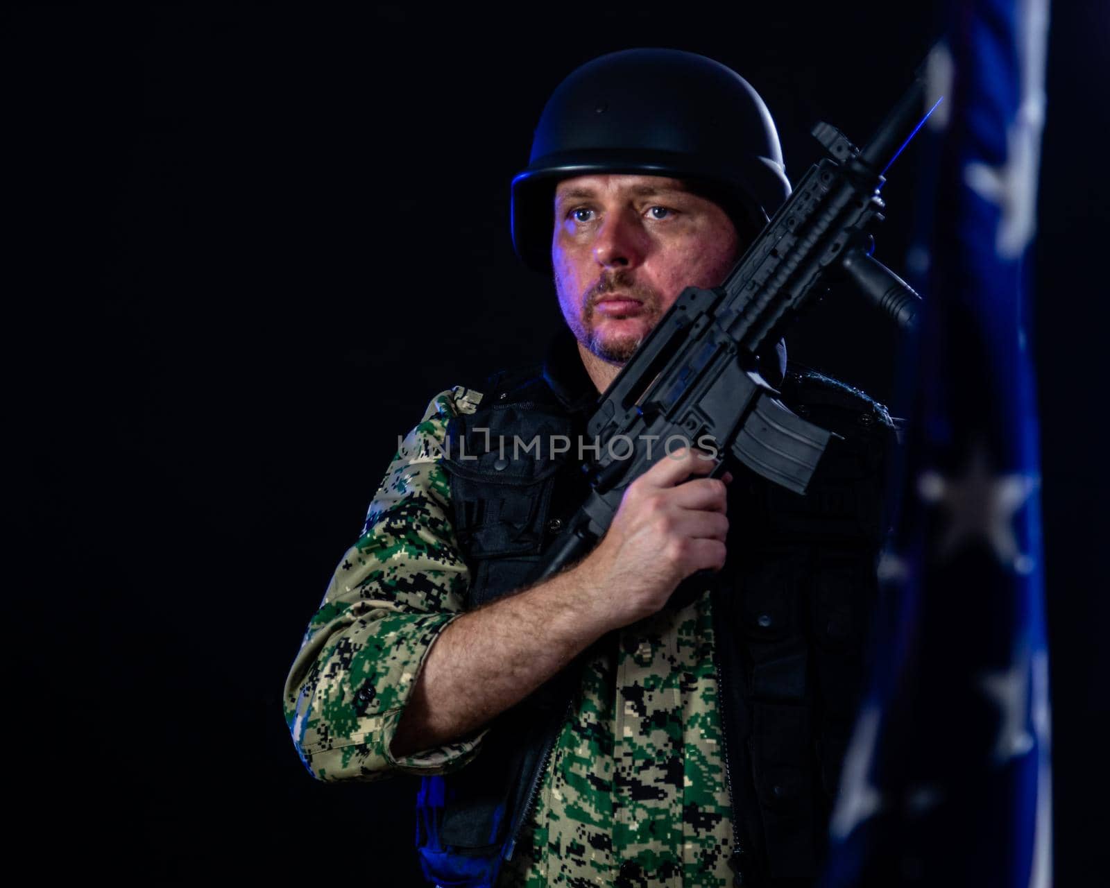 Soldier in army fatigues holding assault rifle and US flag