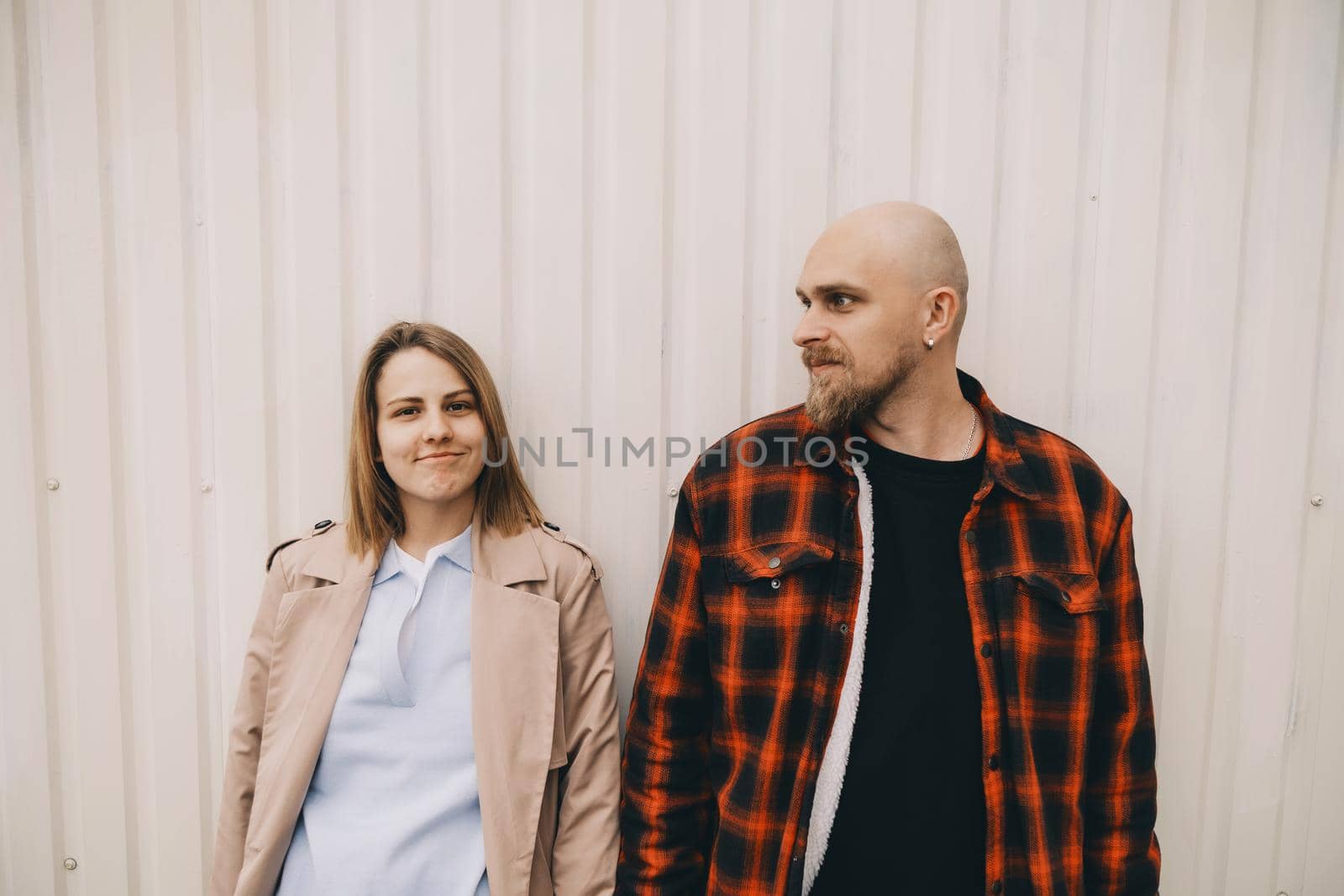 Loving couple stand near wall and look in camera by Symonenko