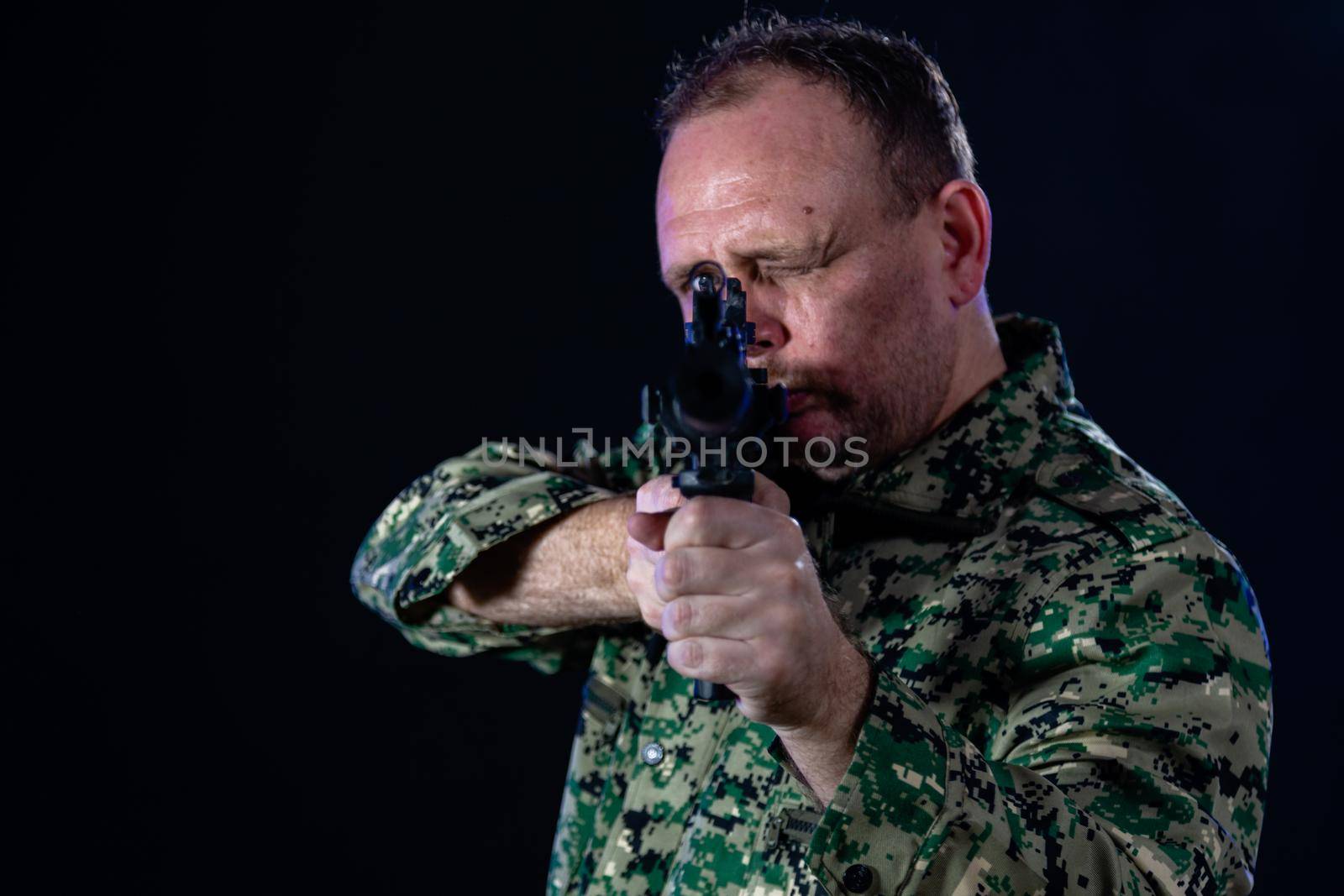 Soldier in army fatigues pointing assault rifle