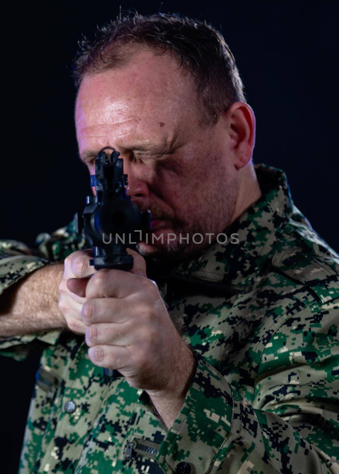 Soldier in army fatigues pointing assault rifle