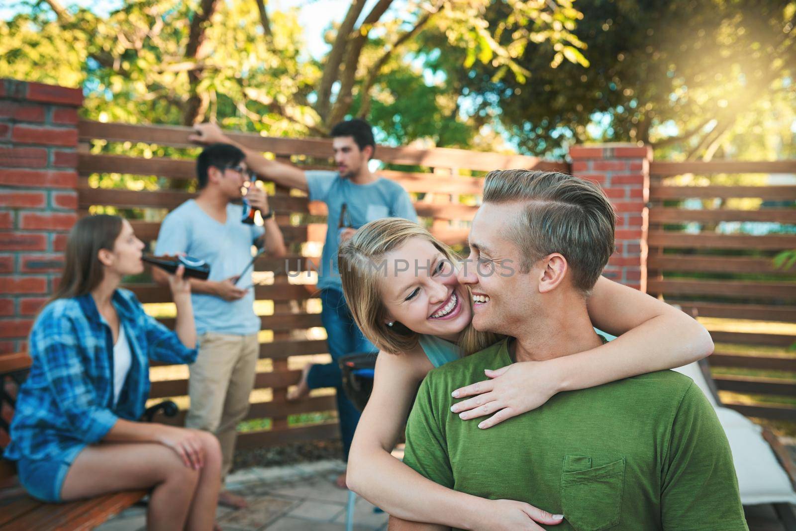 Spend good times with good people. Shot of an affectionate young couple hanging out with their friends at a barbecue. by YuriArcurs