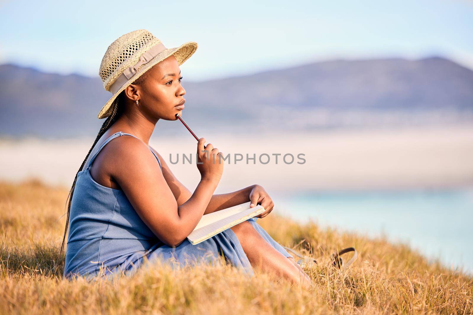 Drowning dialogues. Shot of a young woman writing in her journal at the beach. by YuriArcurs