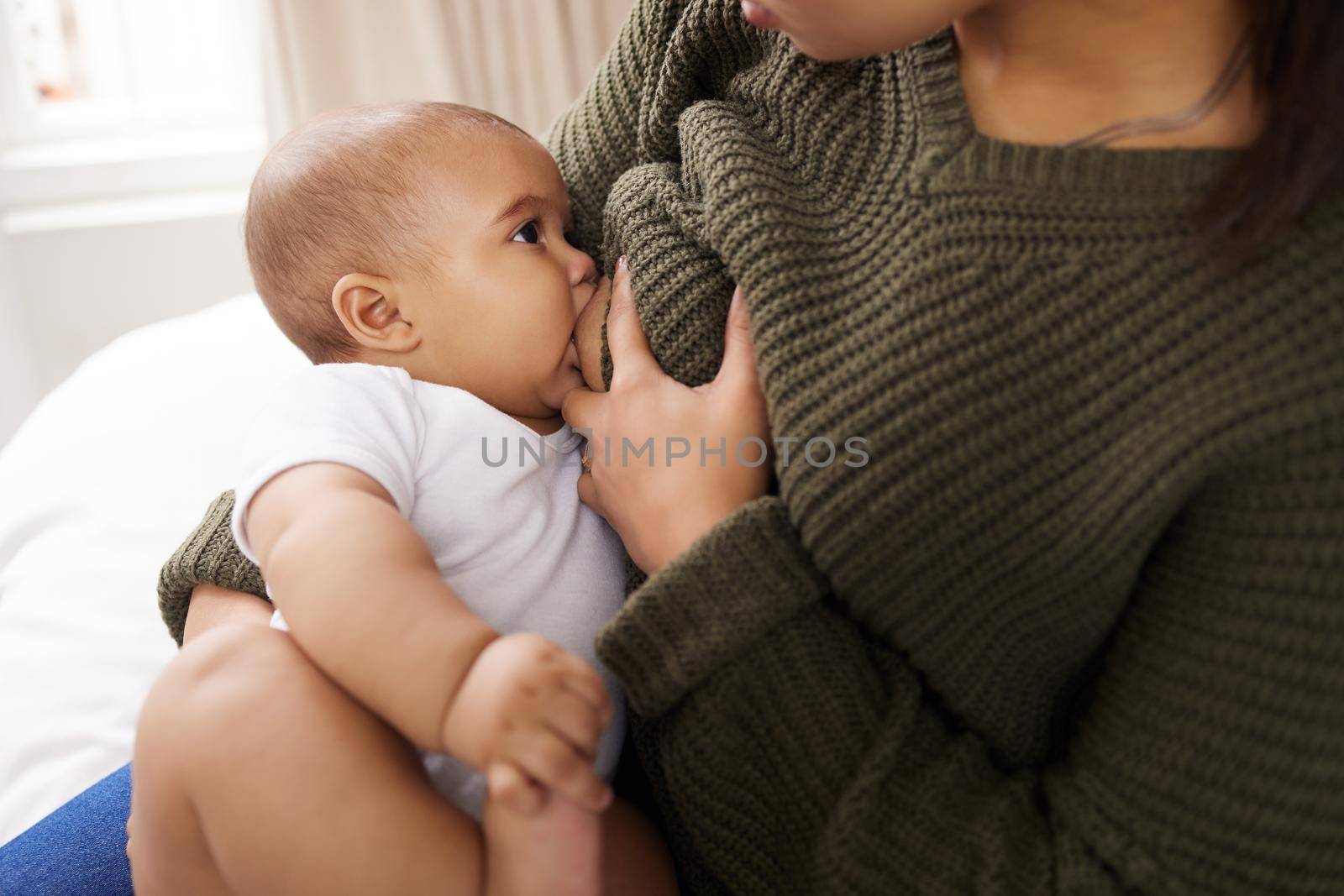 I swear I couldnt love you more than I do right now. Shot of a young woman breastfeeding her adorable baby on the sofa at home. by YuriArcurs