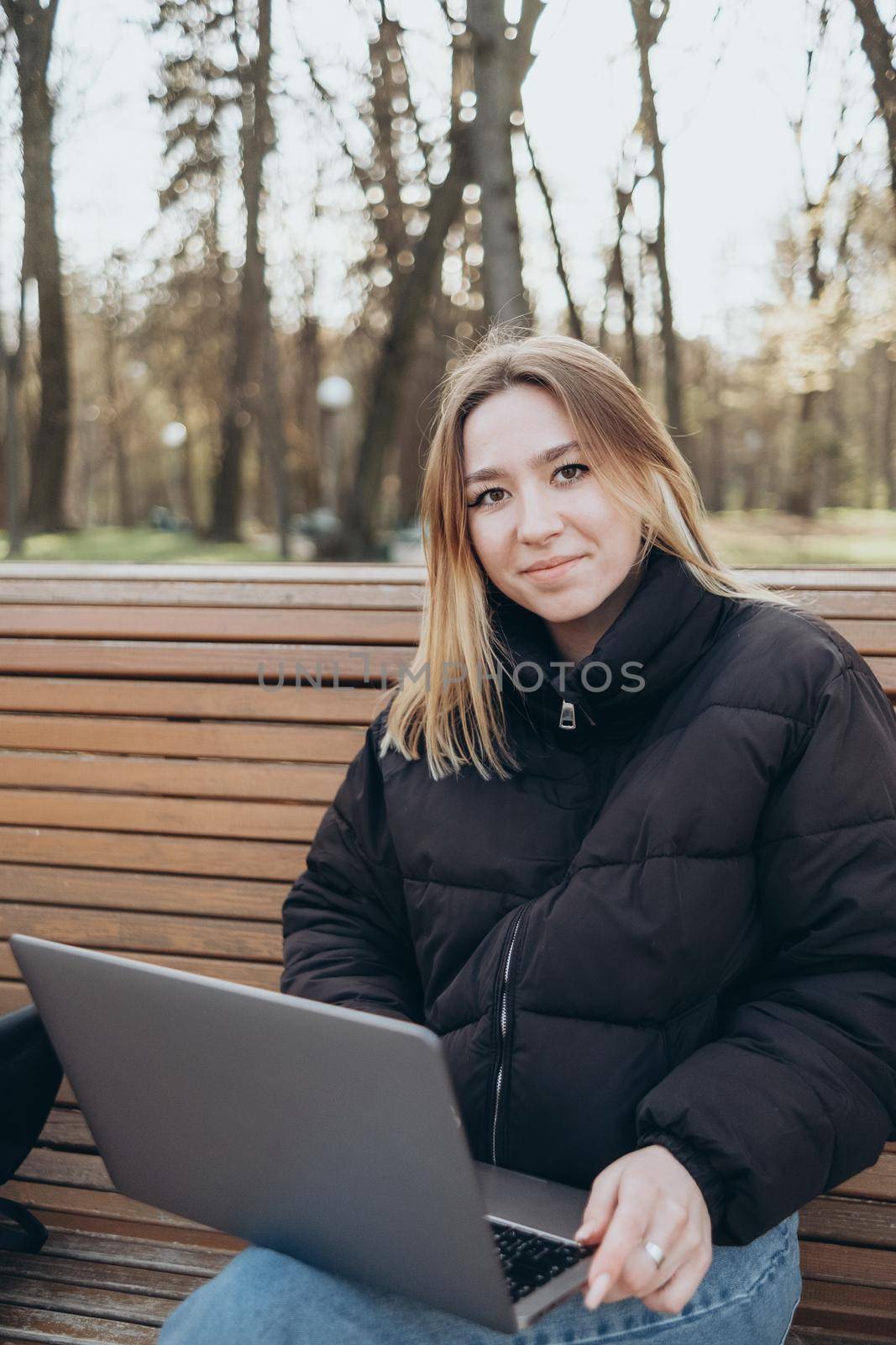Smiling woman studying on laptop at park by Symonenko