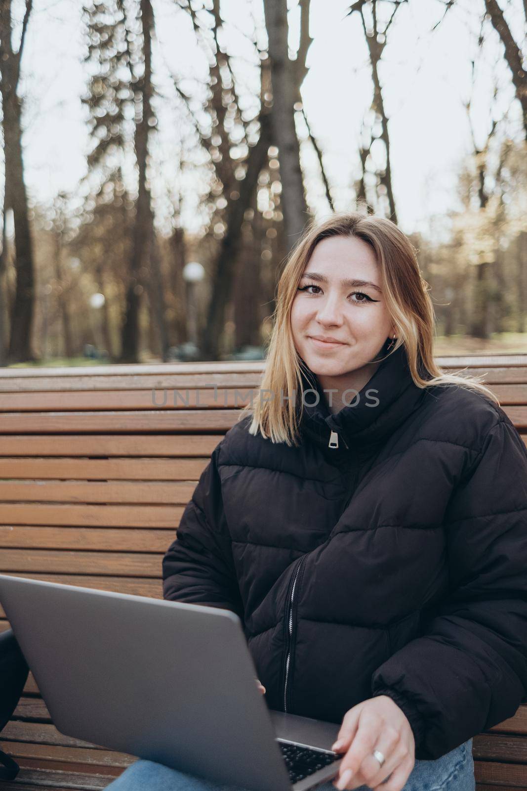 Smiling woman studying on laptop at park by Symonenko