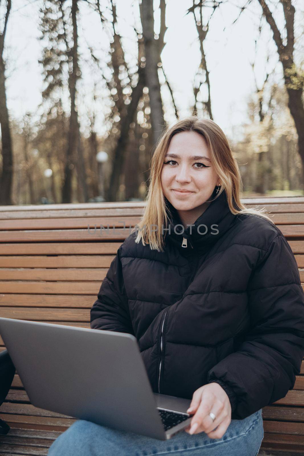 Smiling woman studying on laptop at park by Symonenko