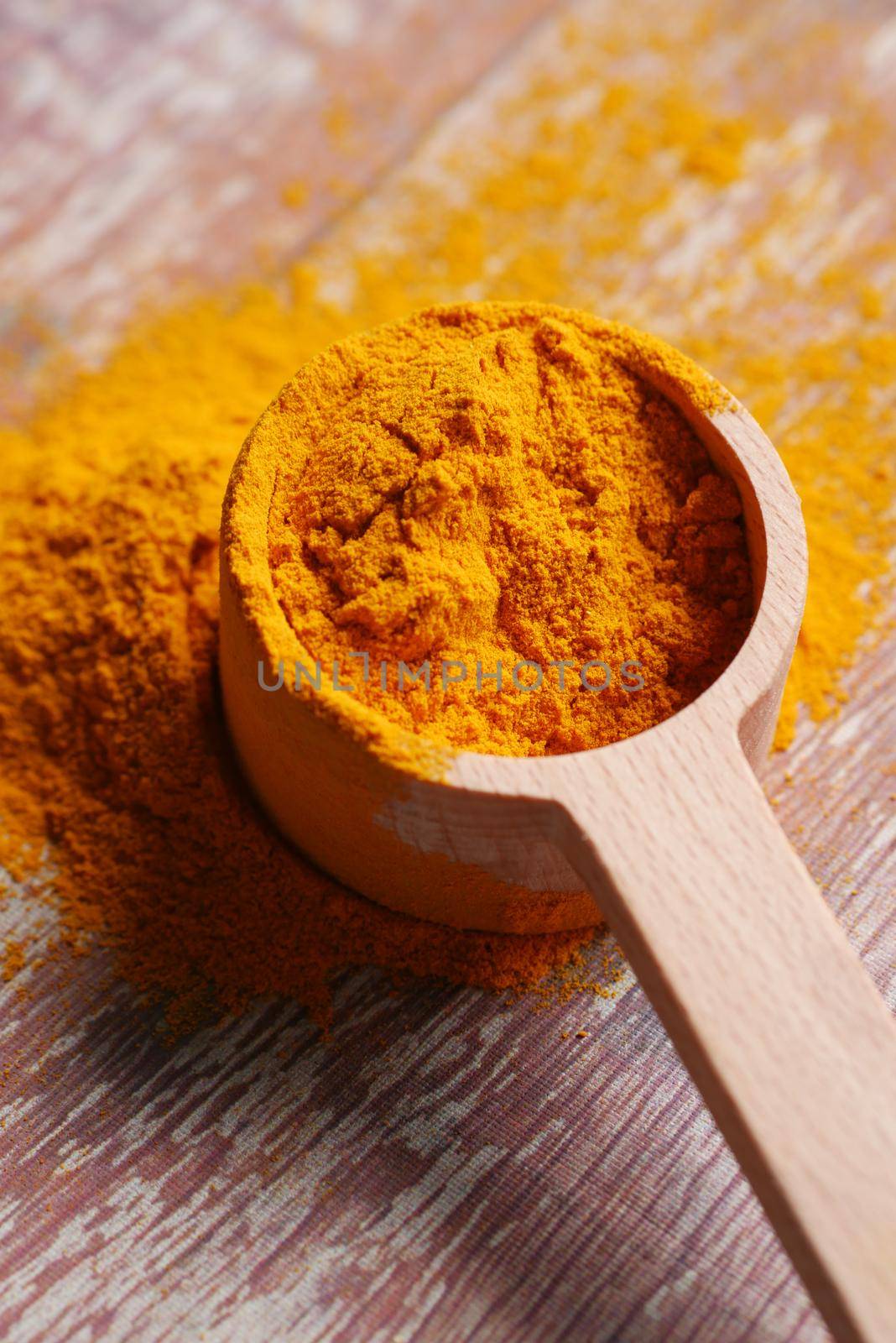 detail shot of turmeric root powder in a spoon on table .