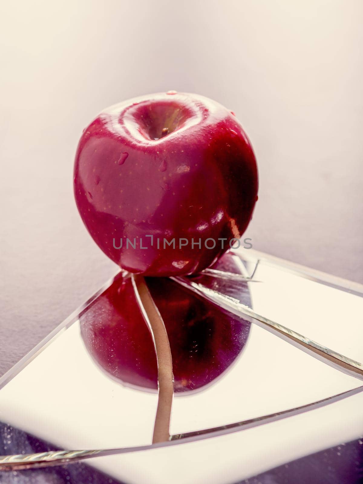 Red apple on cracked broken mirror reflecting