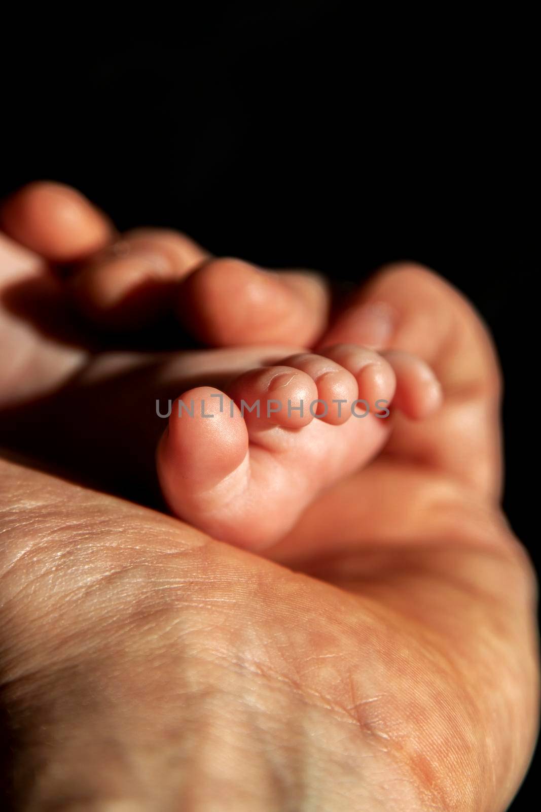 A baby foot softly hold by a man hand