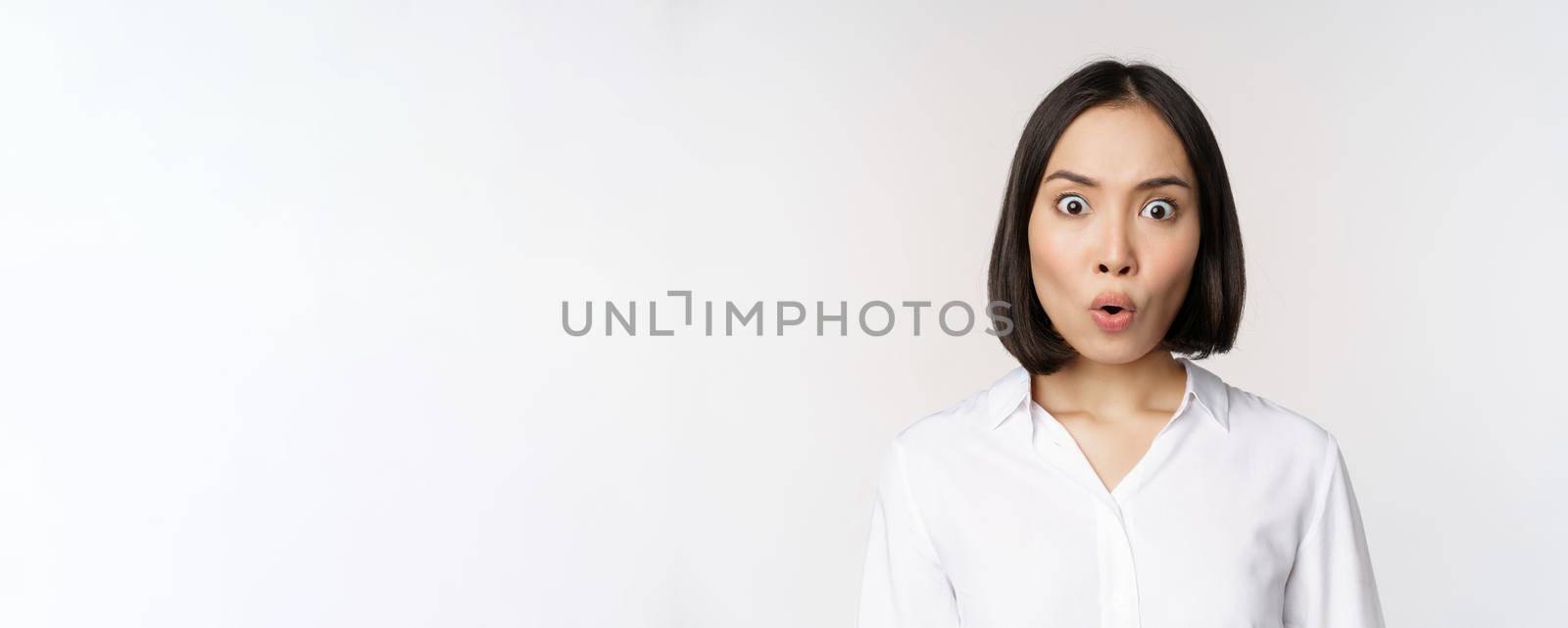 Image of korean woman looking surprised and happy at camera, standing over white background by Benzoix