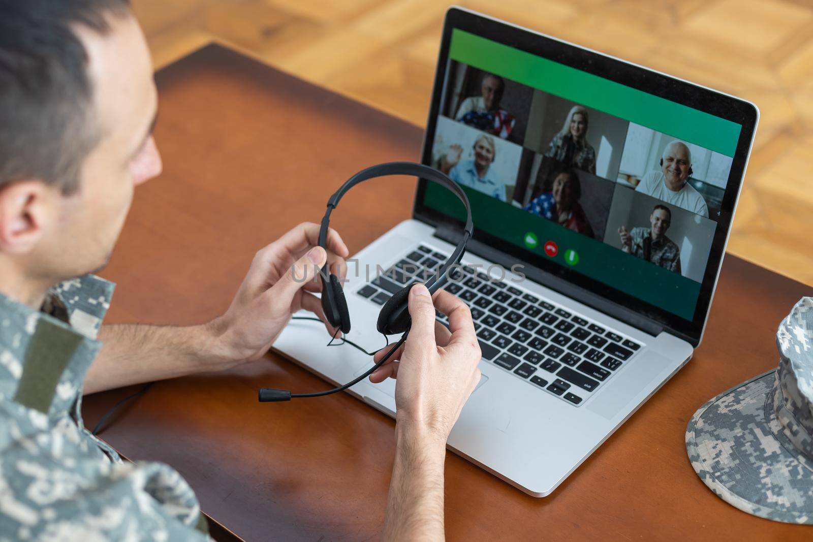 soldier man smiling while making conference call on laptop indoors.