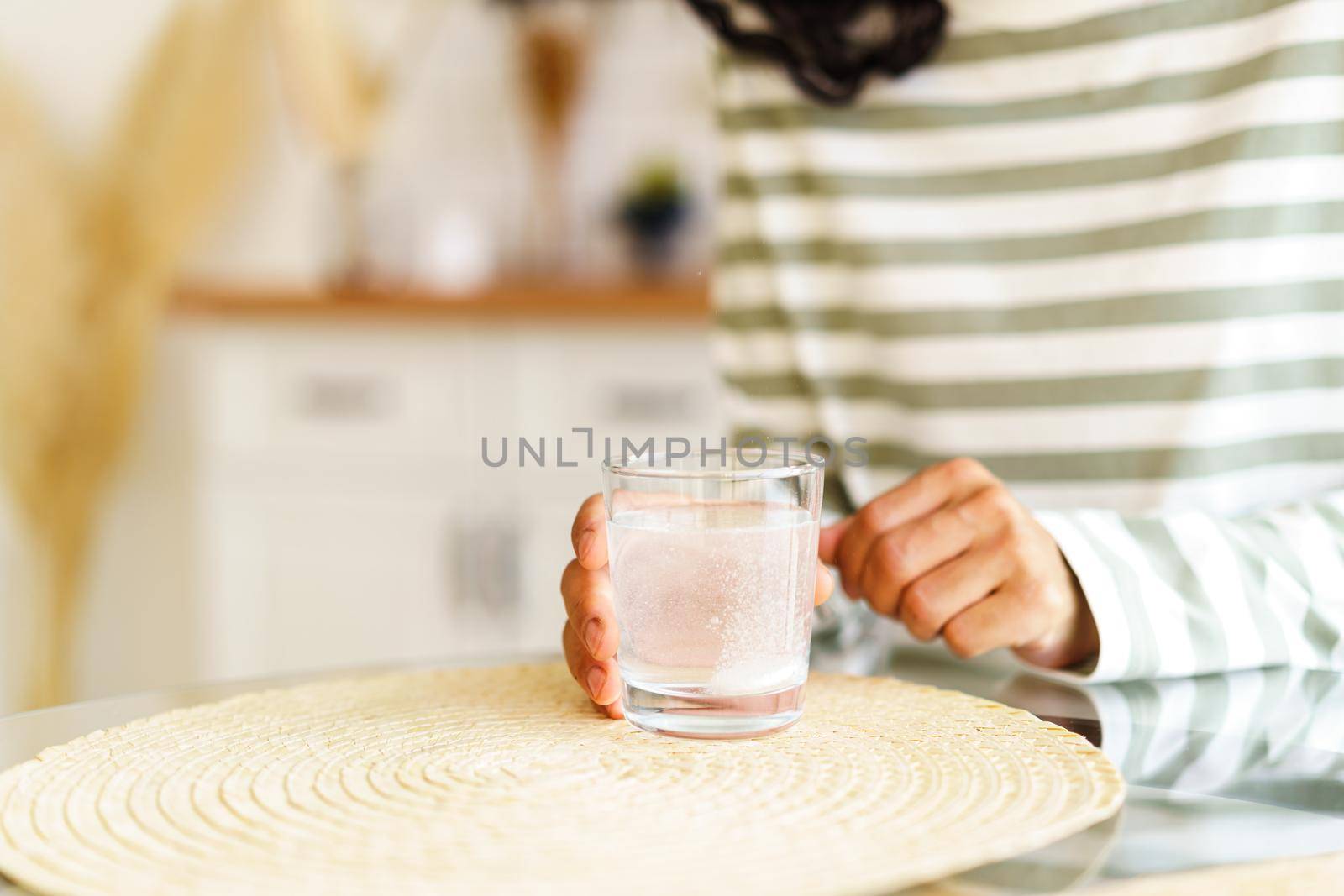 Dissolving fizz drug in glass of water. Unrecognizable female taking medicine at home by NataBene