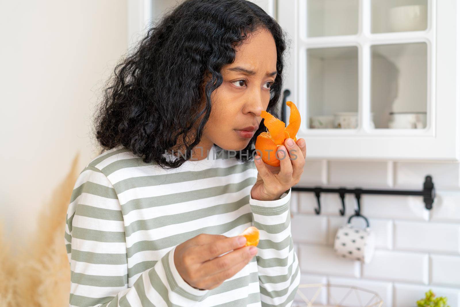 African-american woman suffering from long-term effects after having coronavirus. Concept of loosing sense of smell due to covid19. Female has anosmia disease. Lack of fruit flavor and aroma