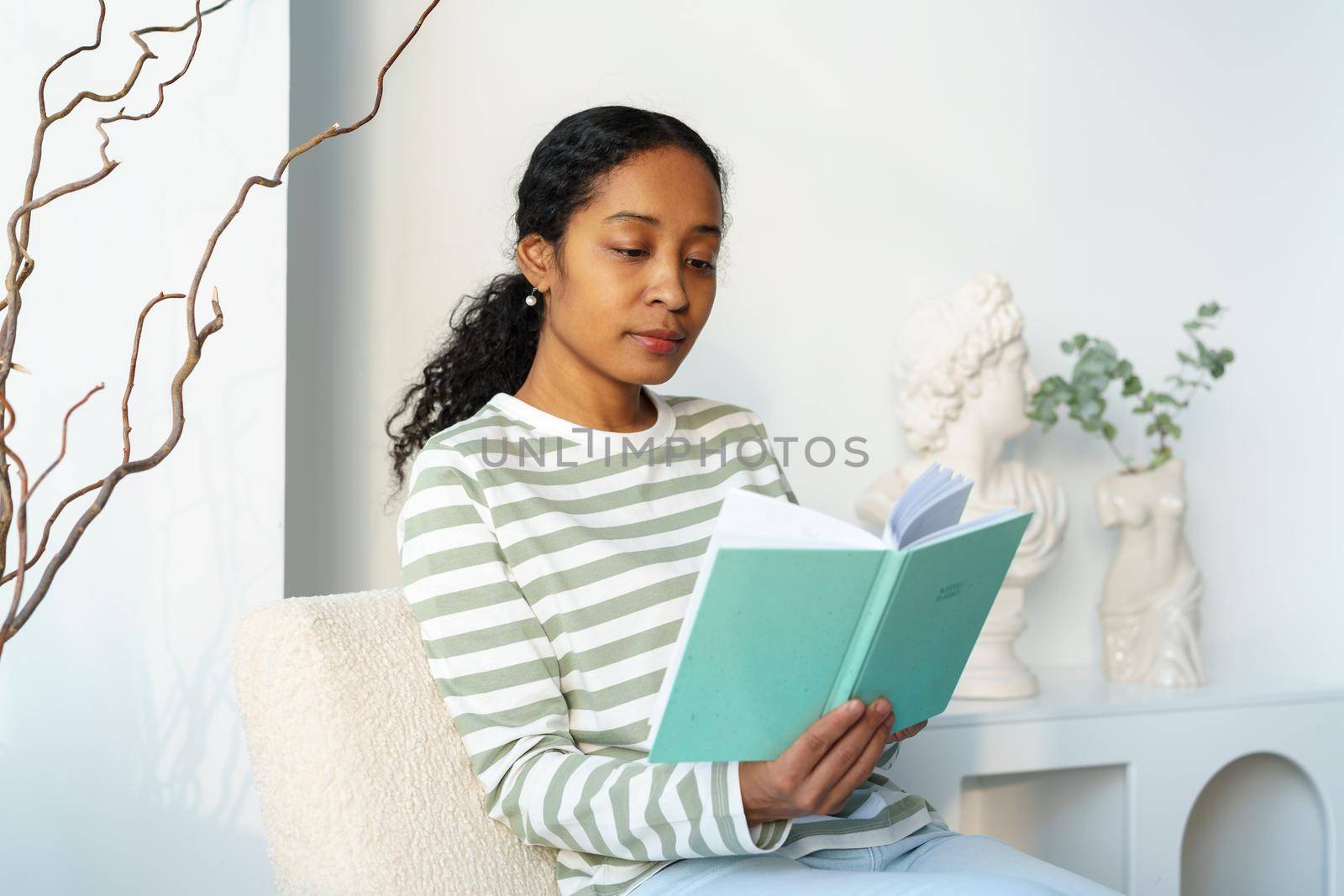 African-american female reading book in free time. Unplugged break. Slow paced lifestyle. Concept of modern young bookworm. Focusing on literature. Finding inspiration while relaxing
