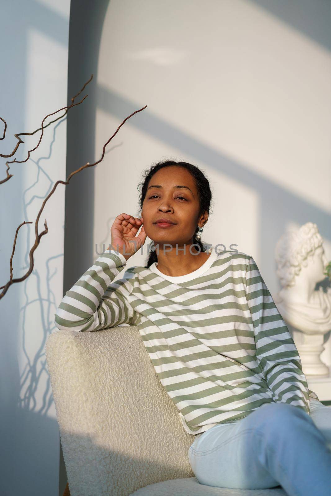 Thoughtful african-american female looking at window. Sunset natural light. Niksen lifestyle by NataBene