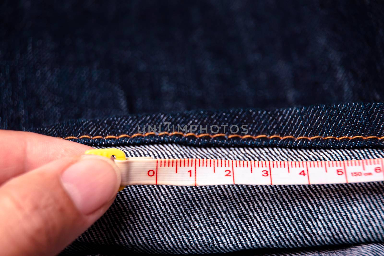 Measurement jeans cloth the length with a measuring tape. by Phutthasatchathum