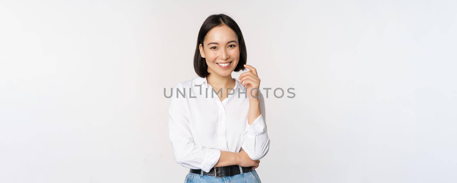 Young asian woman, professional entrepreneur standing in office clothing, smiling and looking confident, white background.