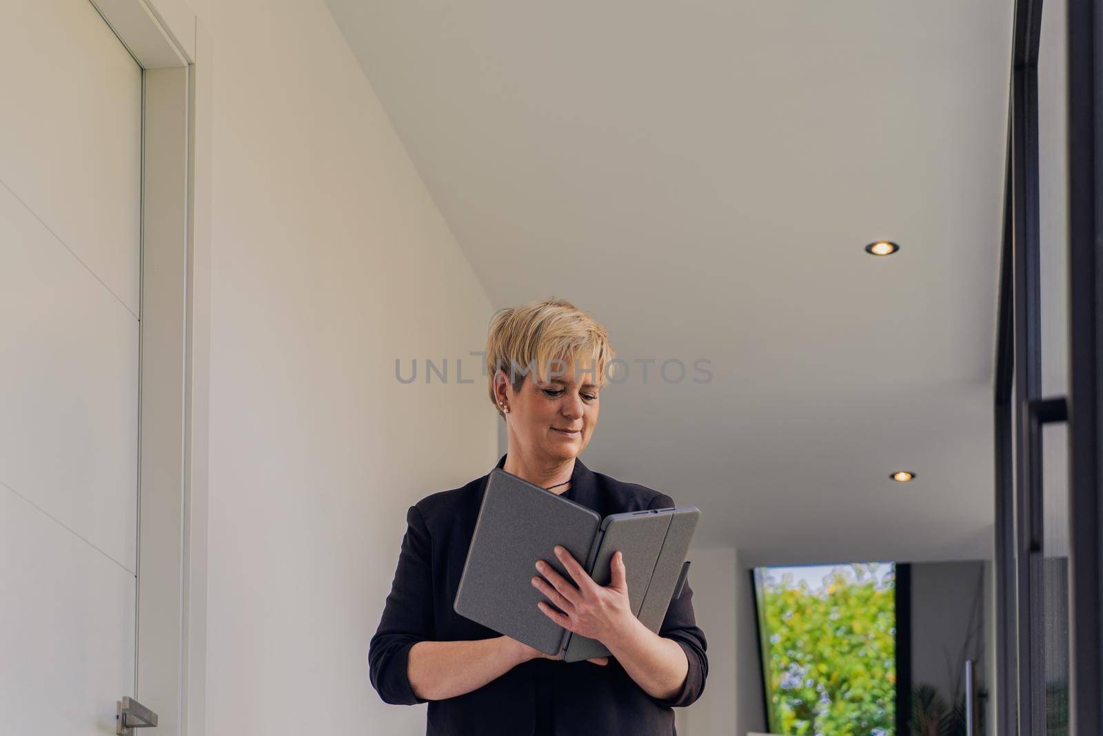 portrait of business woman checking email on her Tablet. owner in her small beauty salon looking at laptop. by CatPhotography