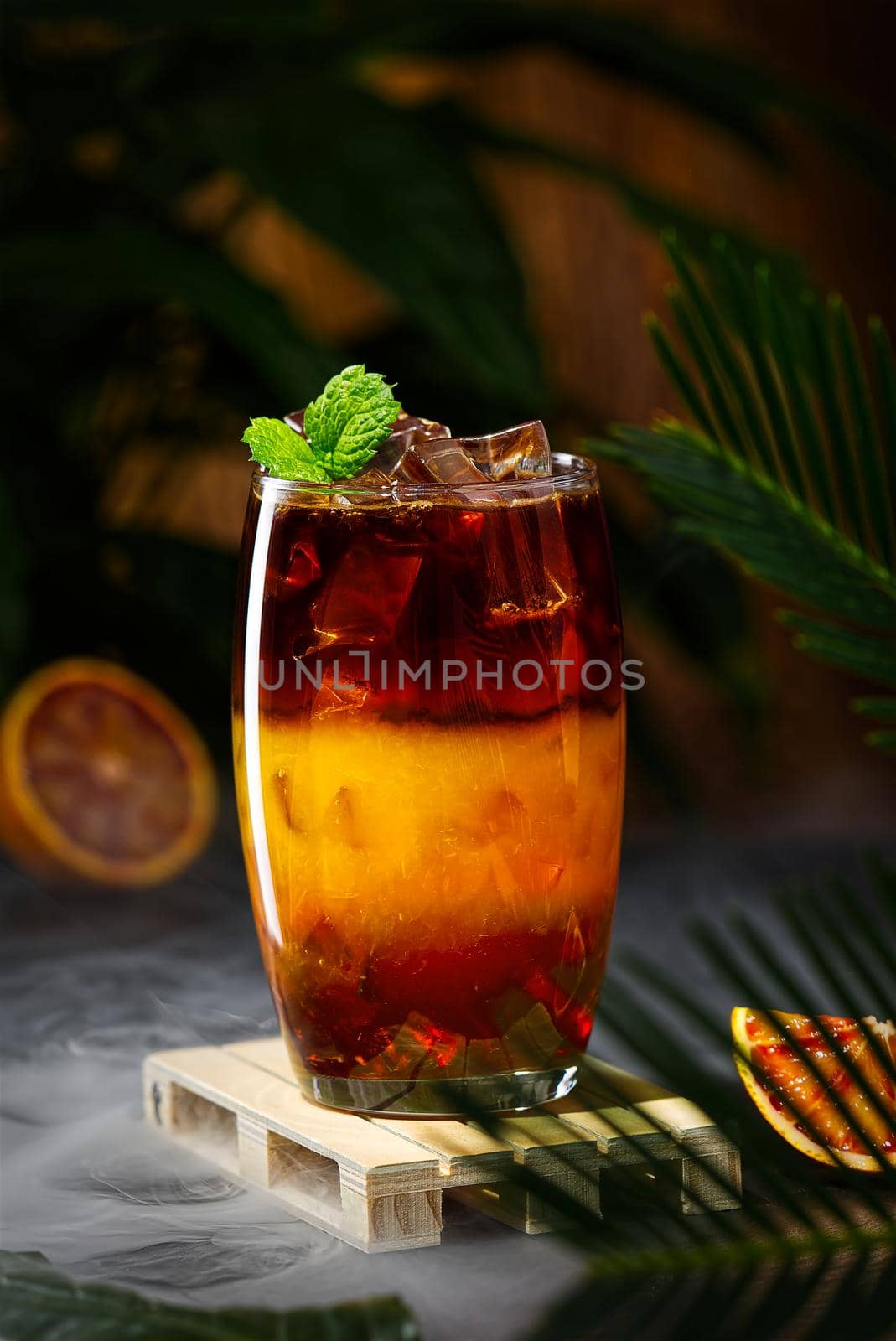 Bumble coffee with ice on a dark tropical background. Espresso, orange juice and syrup in layers by PhotoTime