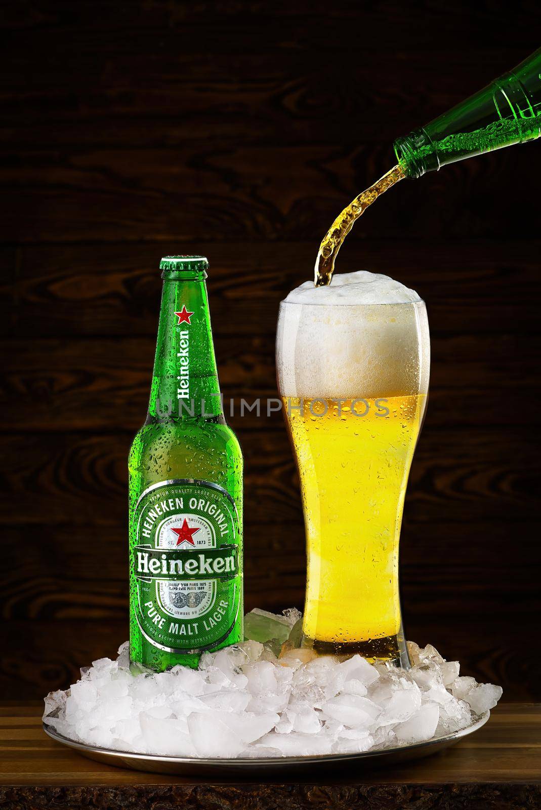Tallinn, Estonia, March 2022. Heineken Lager Beer bottle with glass full of beer in ice. Dutch: Heineken Pilsener produced by the Dutch brewing company Heineken International.