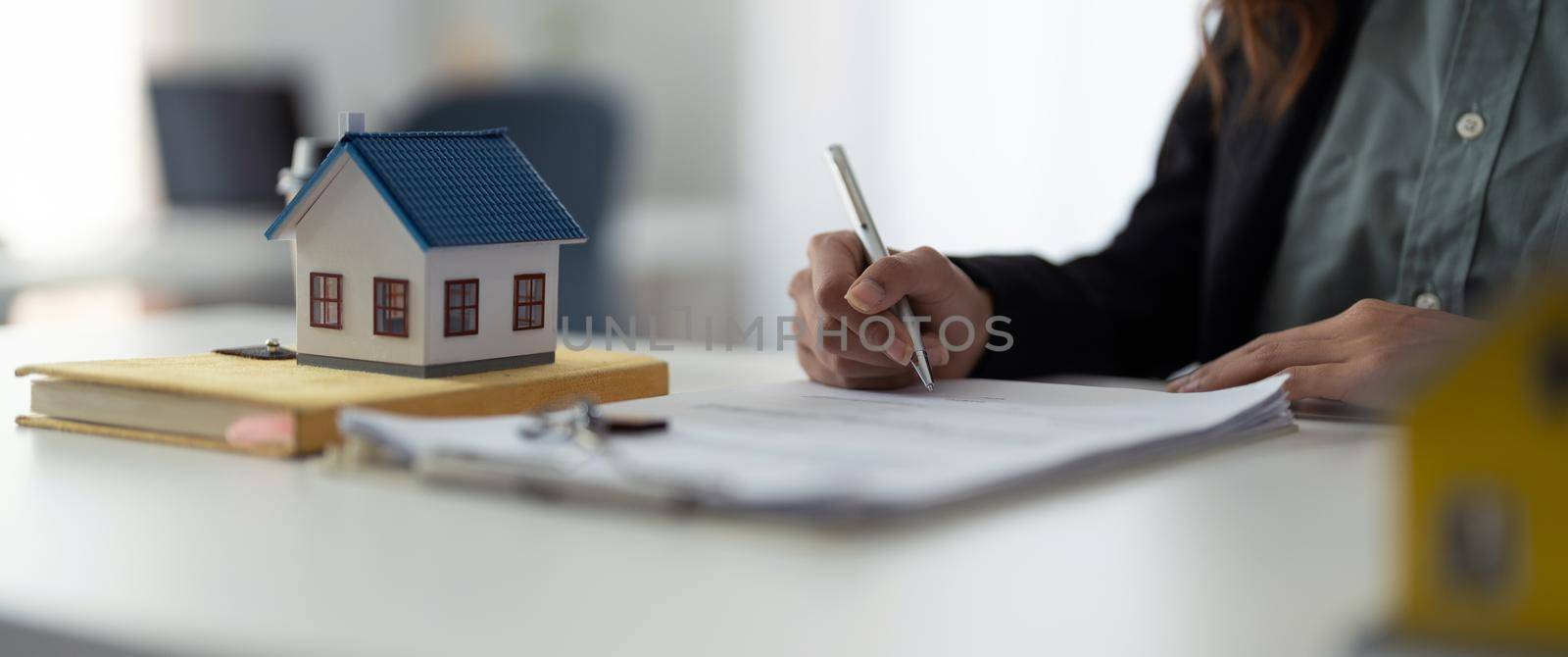 Close up hand of real estate investment and home insurance signing contracts in accordance with the home buying insurance agreements approving purchases for clients by nateemee