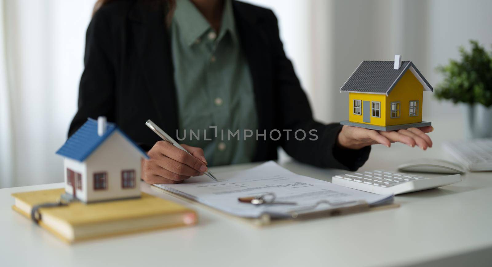 Real estate agent holding house model to his client after signing contract agreement in office,concept for real estate, moving home or renting property.