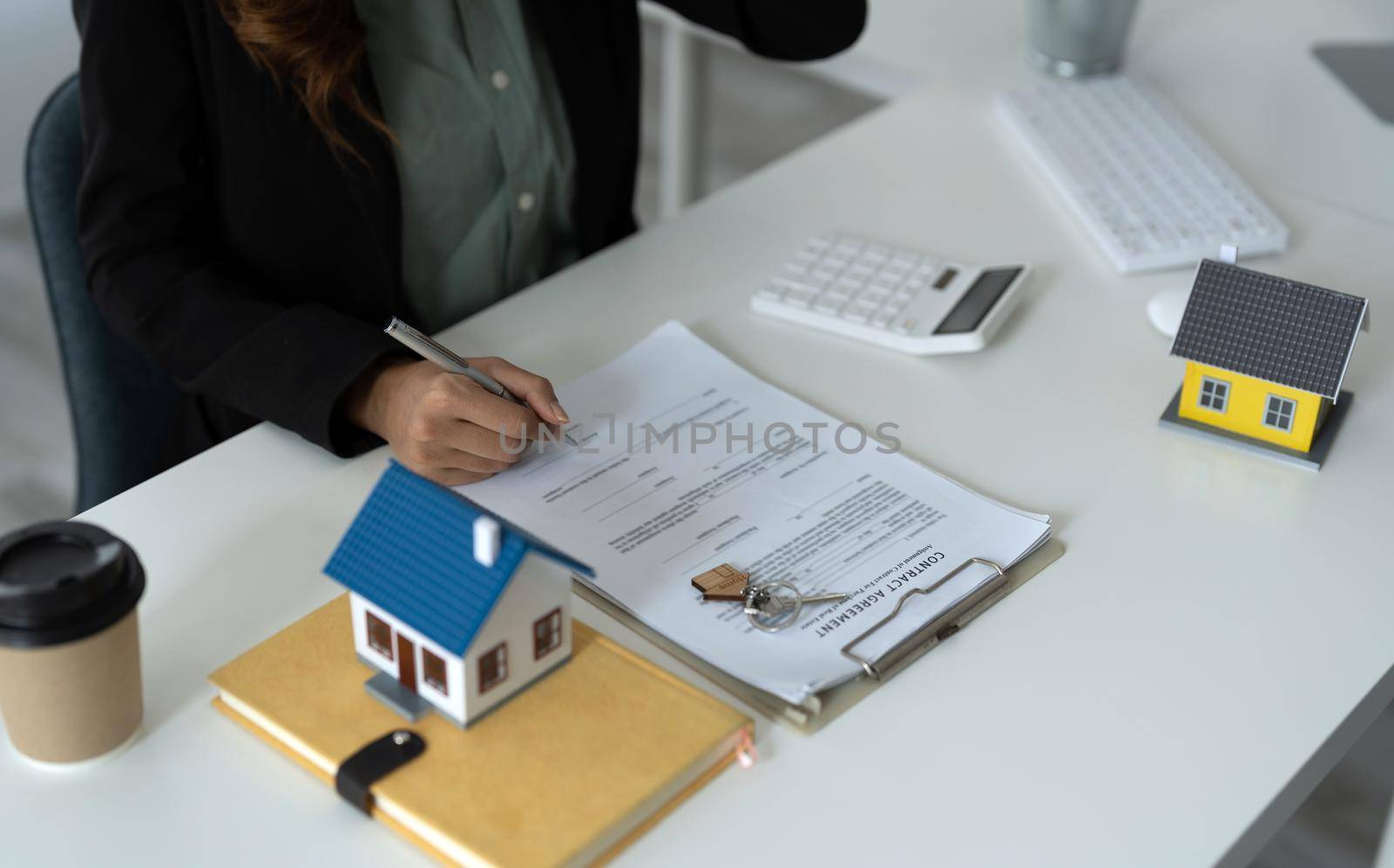 Asian business woman signs contract behind home architectural model - Real estate concept.
