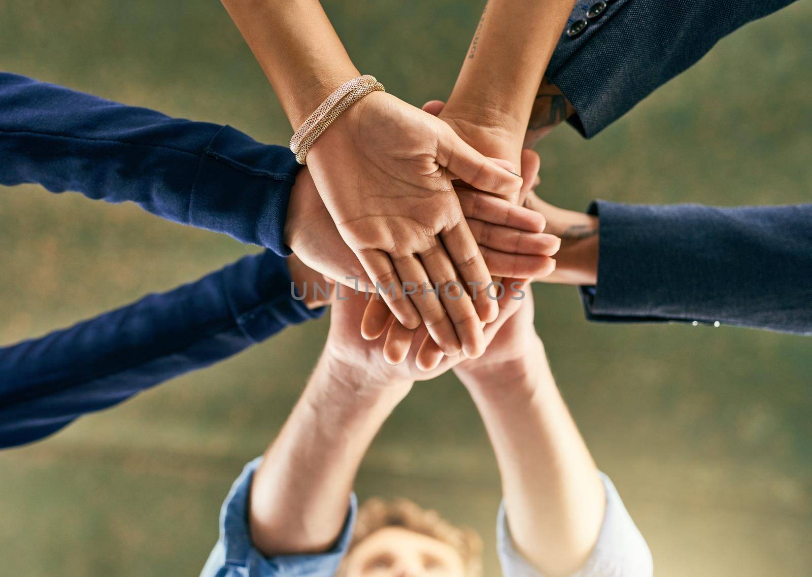 Lets get further together. Closeup shot of a group of people joining their hands in a huddle. by YuriArcurs