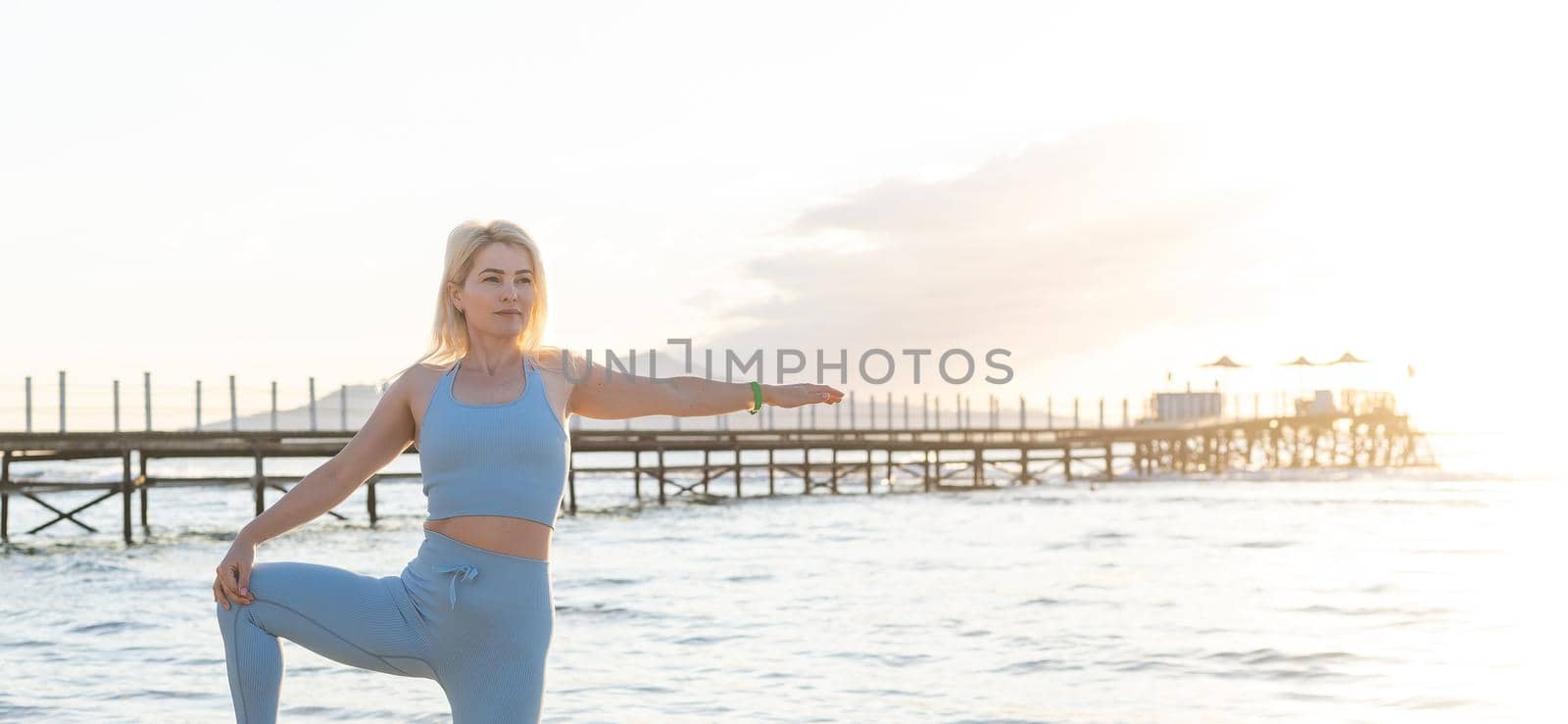 Young beautiful sportive girl training at sunrise over seaside. by Andelov13