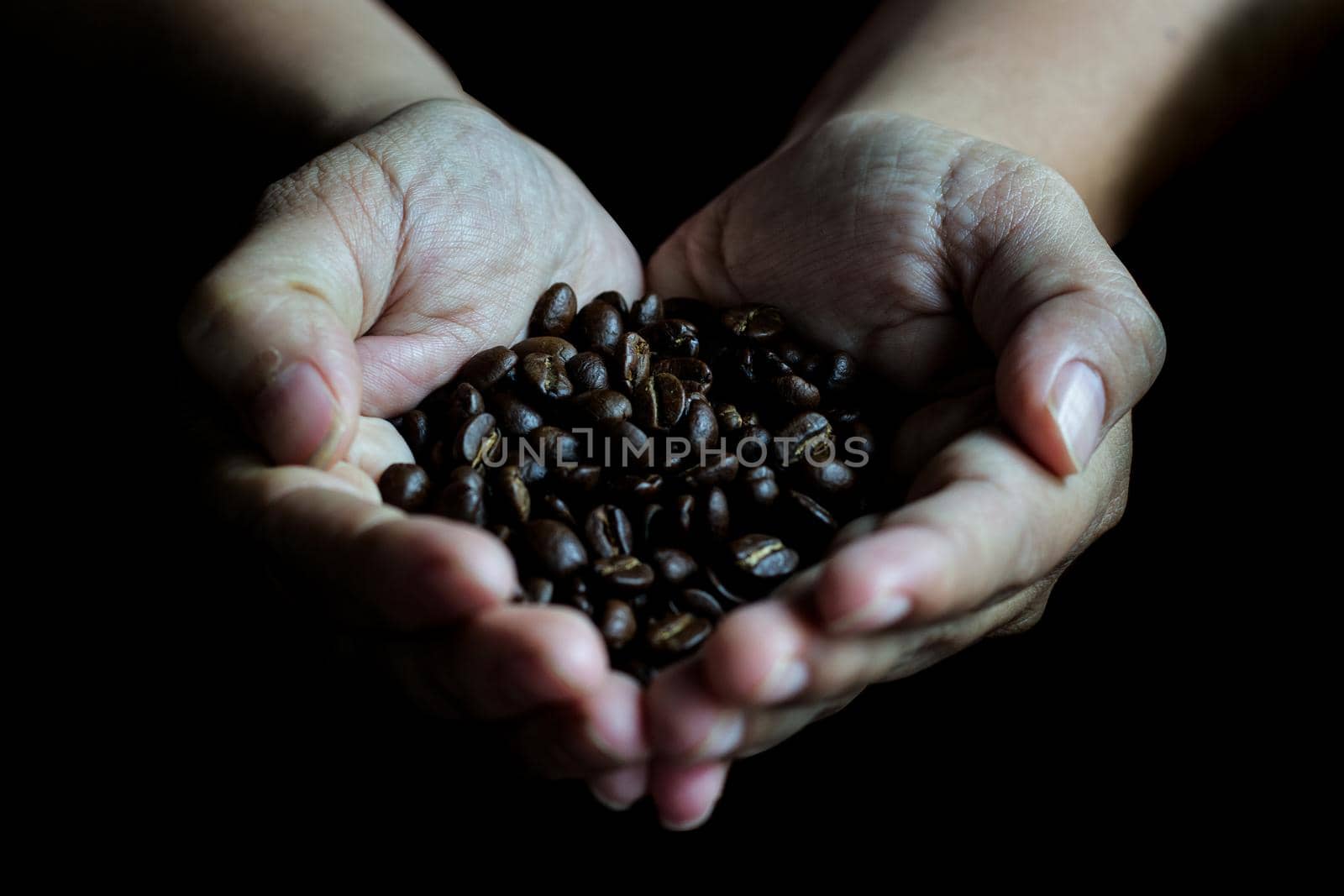 Coffee beans in the hands of heart shaped on wood table dark style and vintage