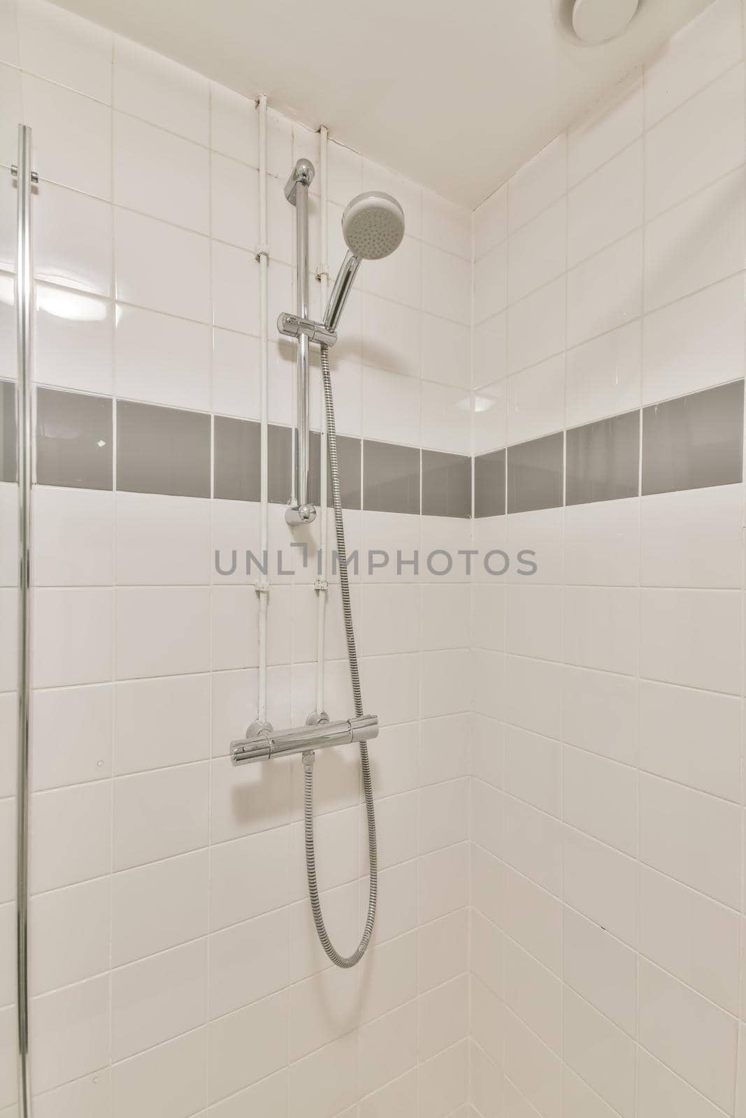 The interior of the bathroom made of white tiles with a shower in a modern house