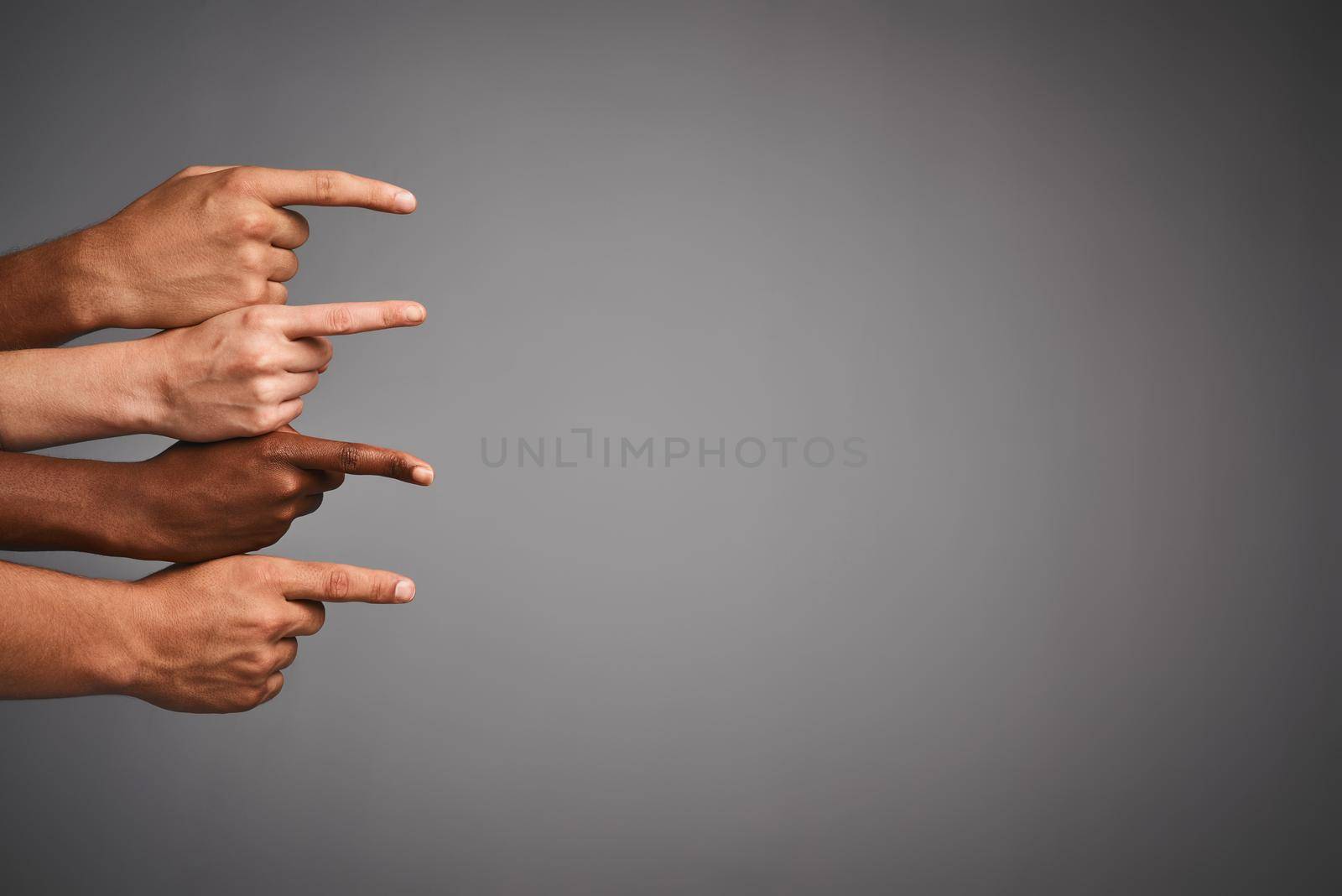 Studio shot of unidentifiable hands pointing sideways towards blank copyspace.