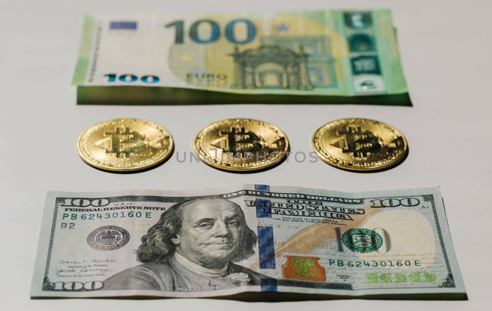 Digital cryptocurrency gold bitcoin lying between US Dollar and Euro banknotes. Difference between virtual money and cash. Concept of new virtual money.