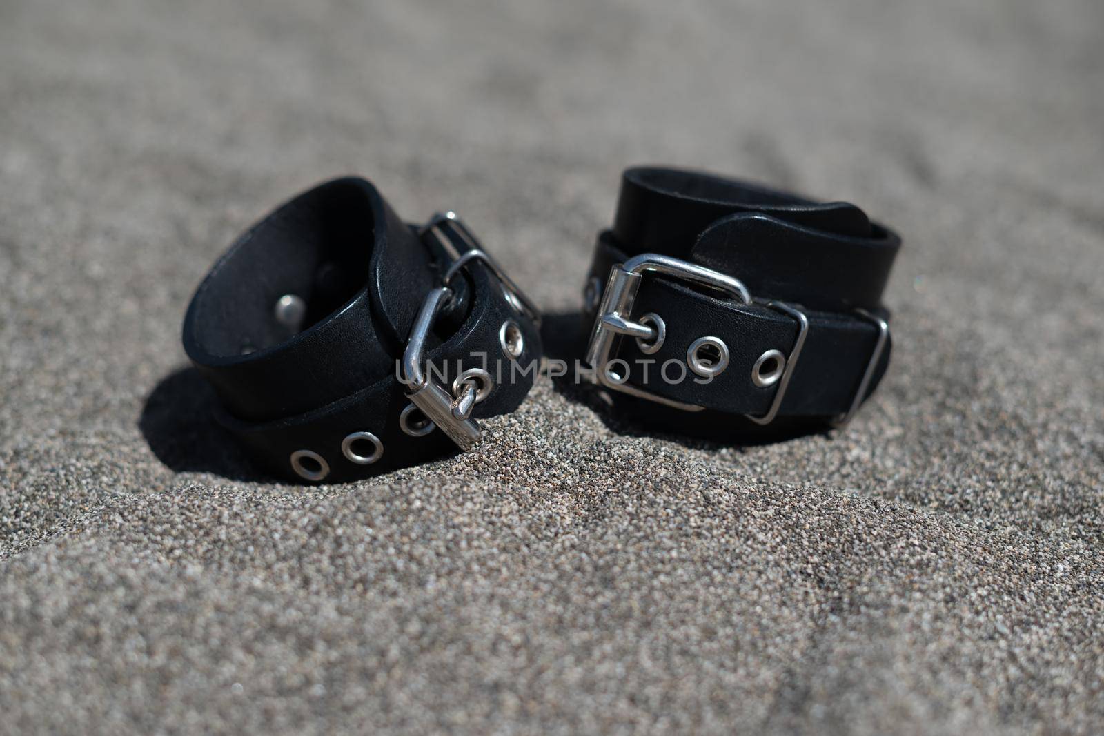 leather handcuffs for bdsm sex toys on a sandy beach