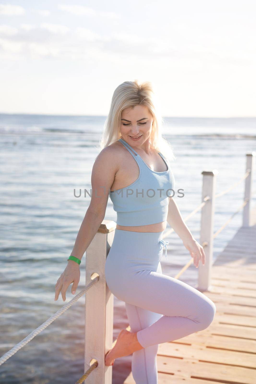 Portrait of fitness woman stretching out by the sea by Andelov13