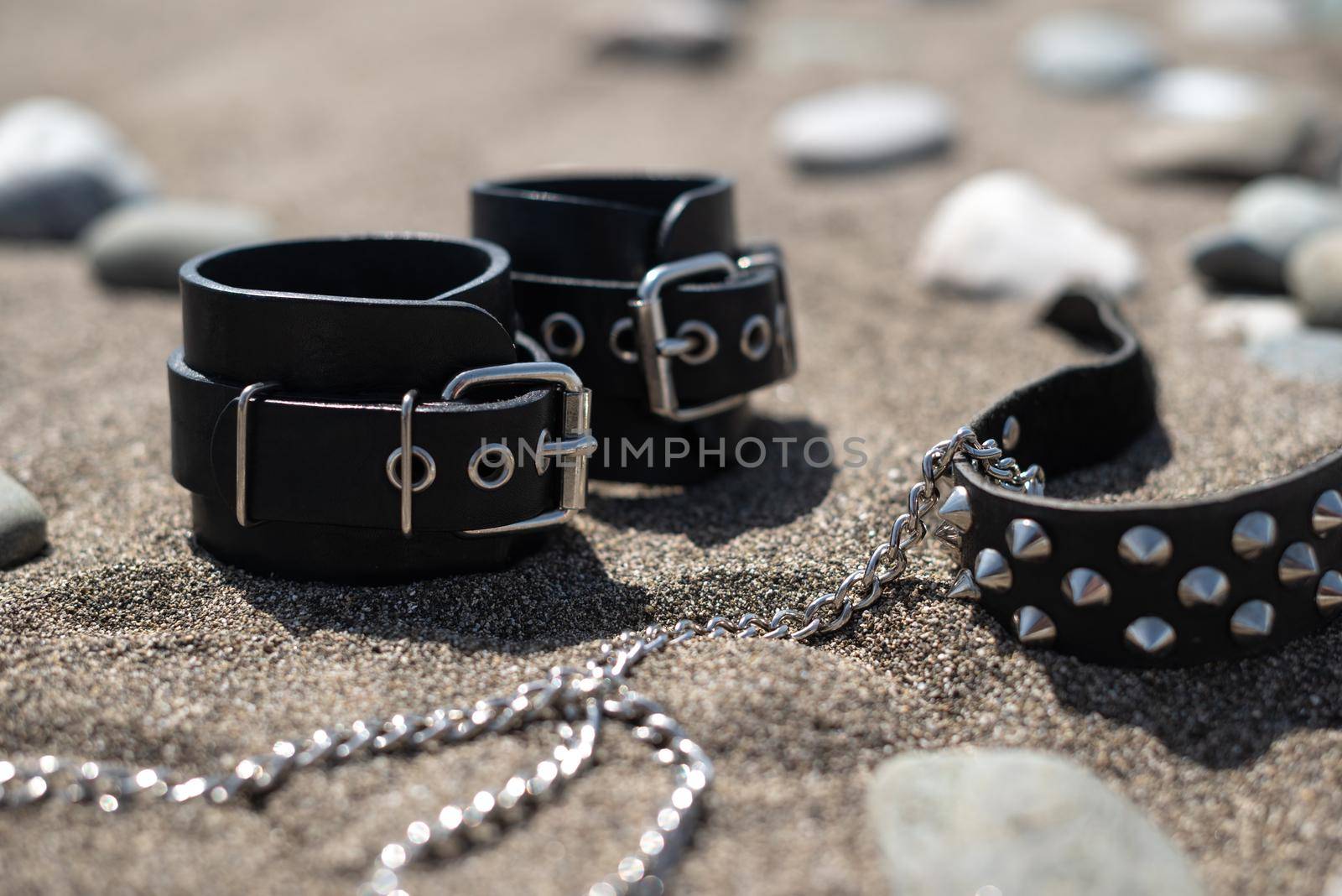leather handcuffs for bdsm sex toys on a sandy beach by Rotozey