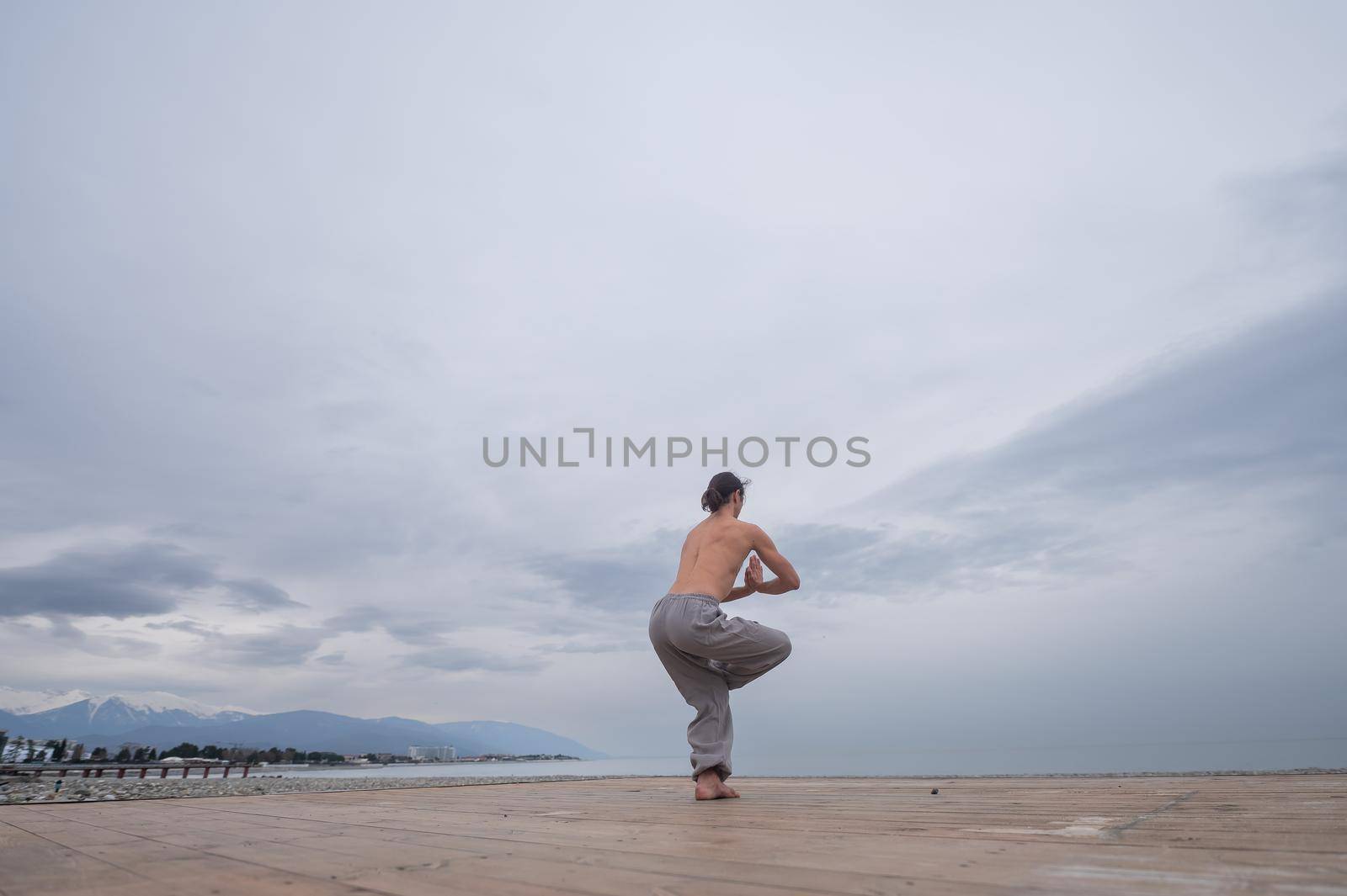 Caucasian man with naked torso practicing wushu on the seashore