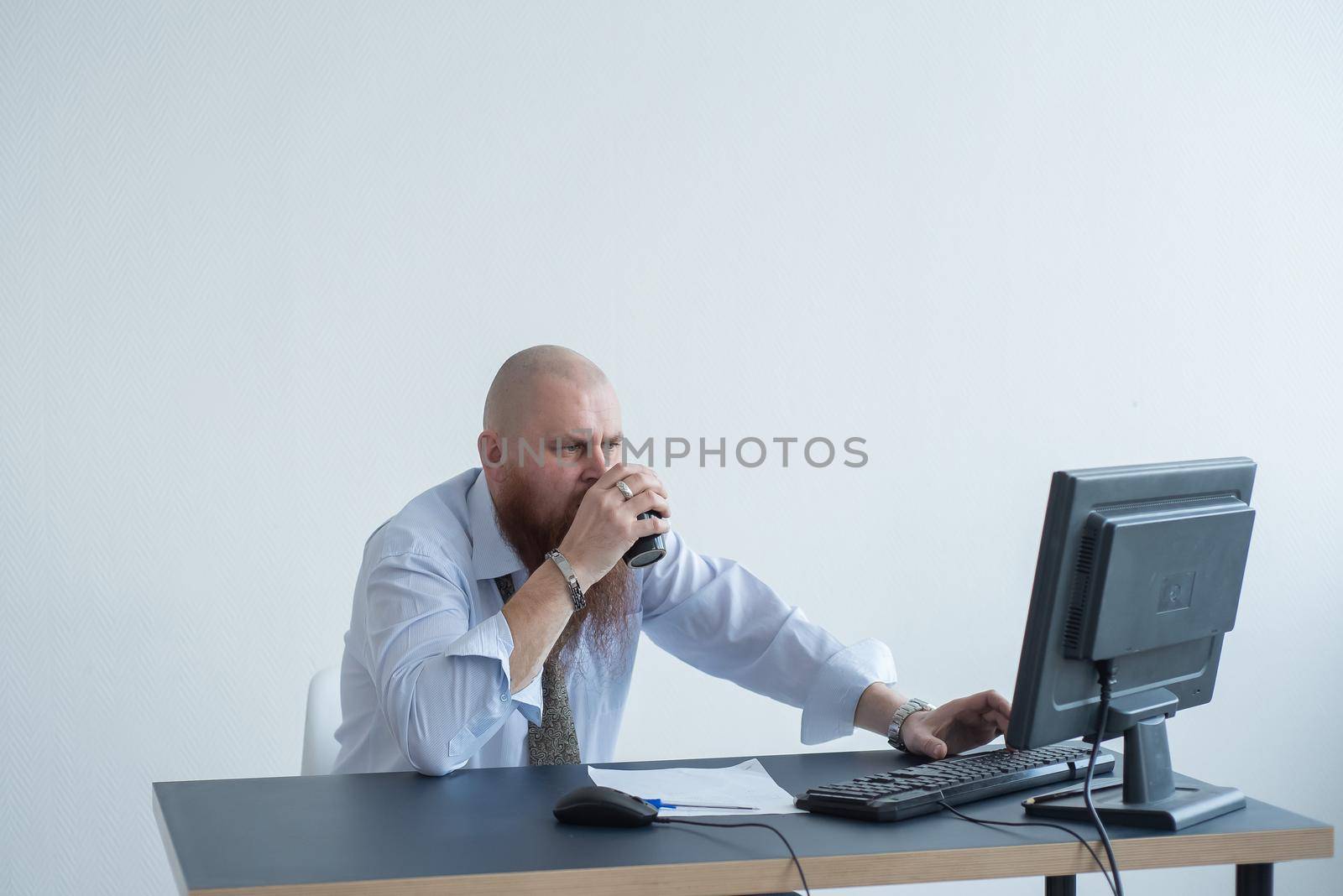 Problems for the office worker. A bald man in a white shirt sits at a desk with a computer and is stressed because of failure. A nervous breakdown
