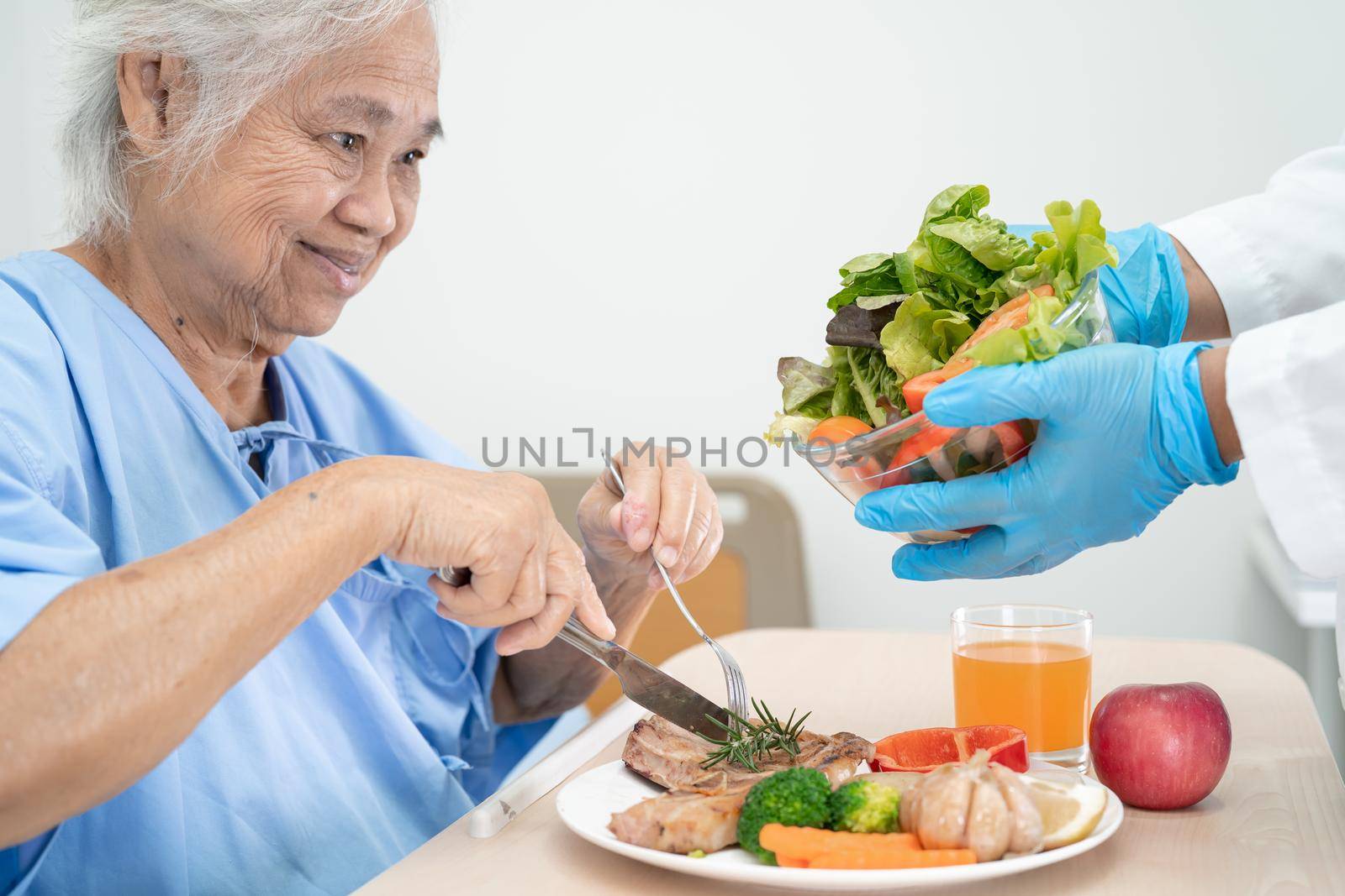 Asian senior or elderly old lady woman patient eating breakfast and vegetable healthy food with hope and happy while sitting and hungry on bed in hospital. by pamai