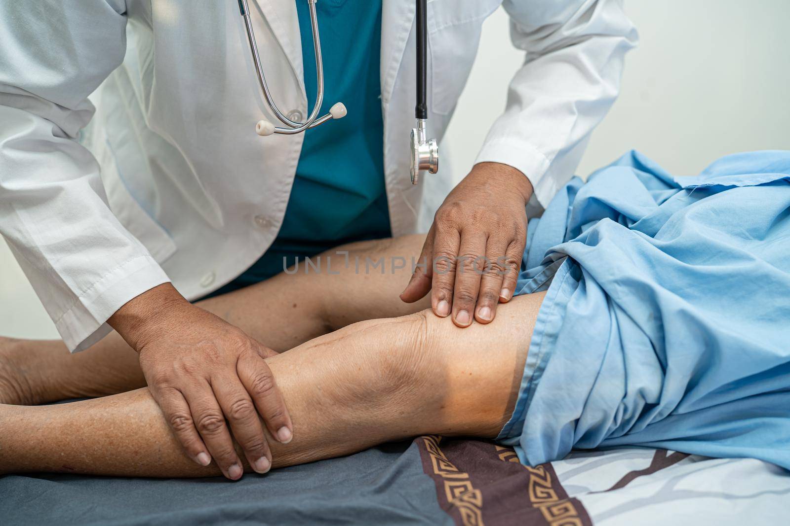 Asian doctor physiotherapist examining, massaging and treatment knee and leg of senior patient in orthopedist medical clinic nurse hospital. by pamai