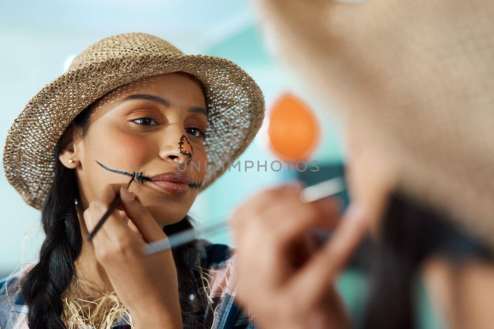 Shot of a young woman applying halloween makeup at home.