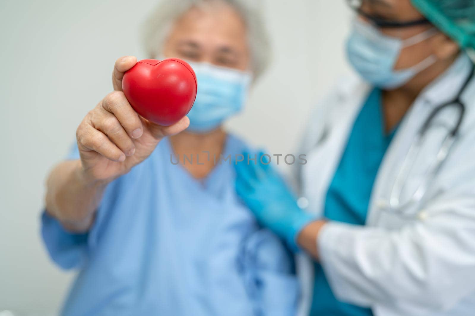 Doctor give red heart to Asian senior or elderly old lady woman patient, healthy strong medical concept by pamai