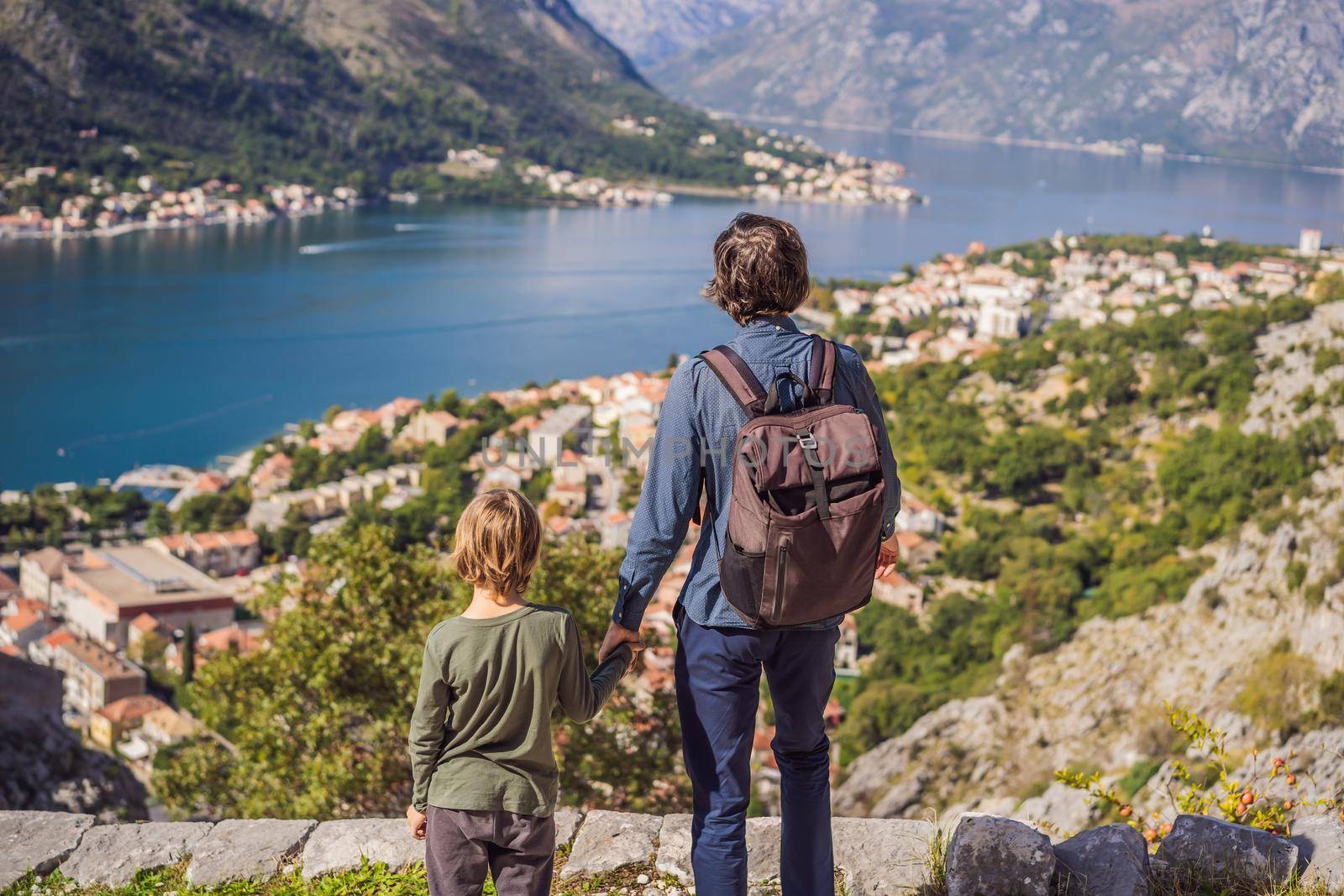 Dad and son travellers enjoys the view of Kotor. Montenegro. Bay of Kotor, Gulf of Kotor, Boka Kotorska and walled old city. Travel with kids to Montenegro concept. Fortifications of Kotor is on UNESCO World Heritage List since 1979.