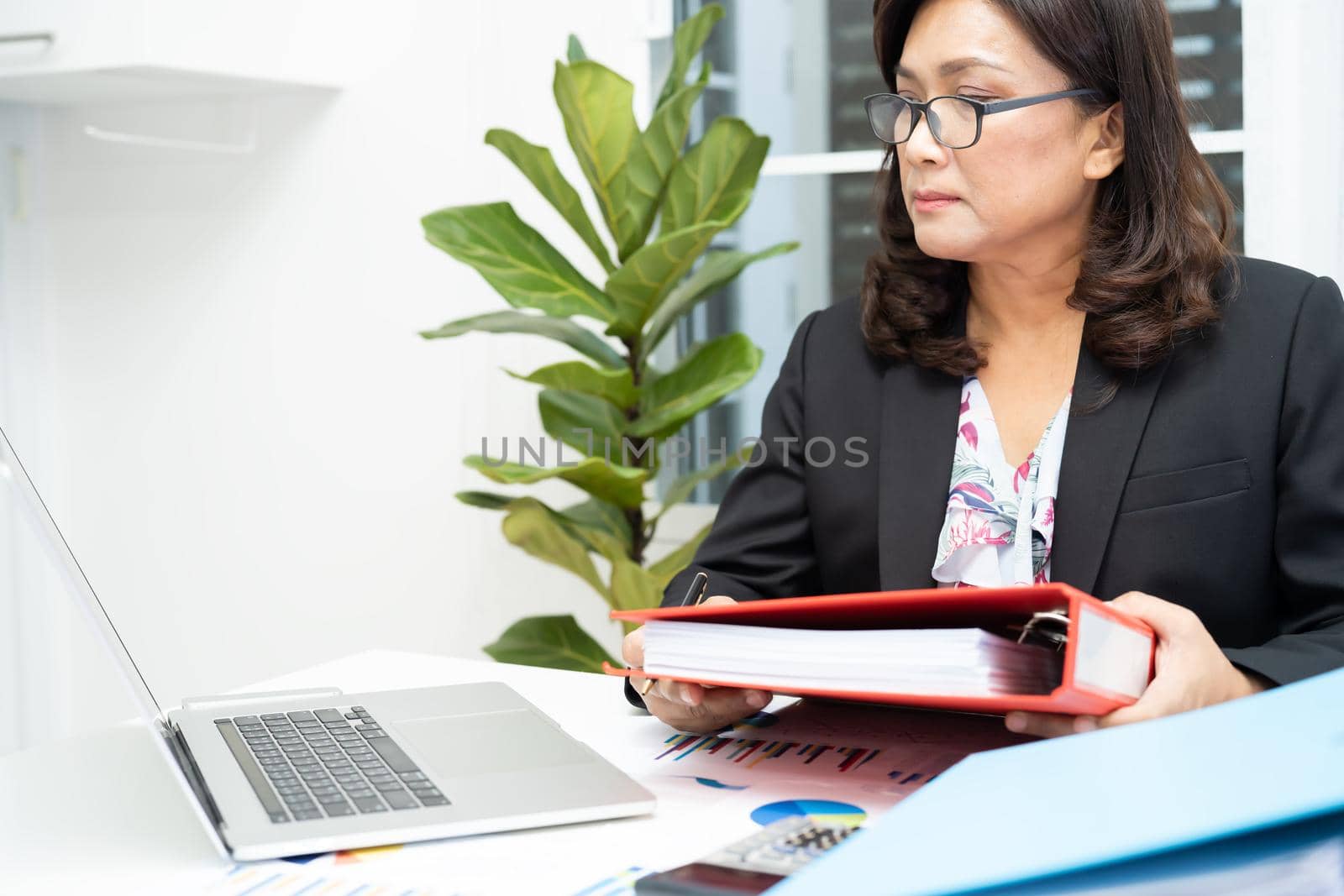 Asian accountant working and analyzing financial reports project accounting with chart graph and laptop in modern office, finance and business concept.