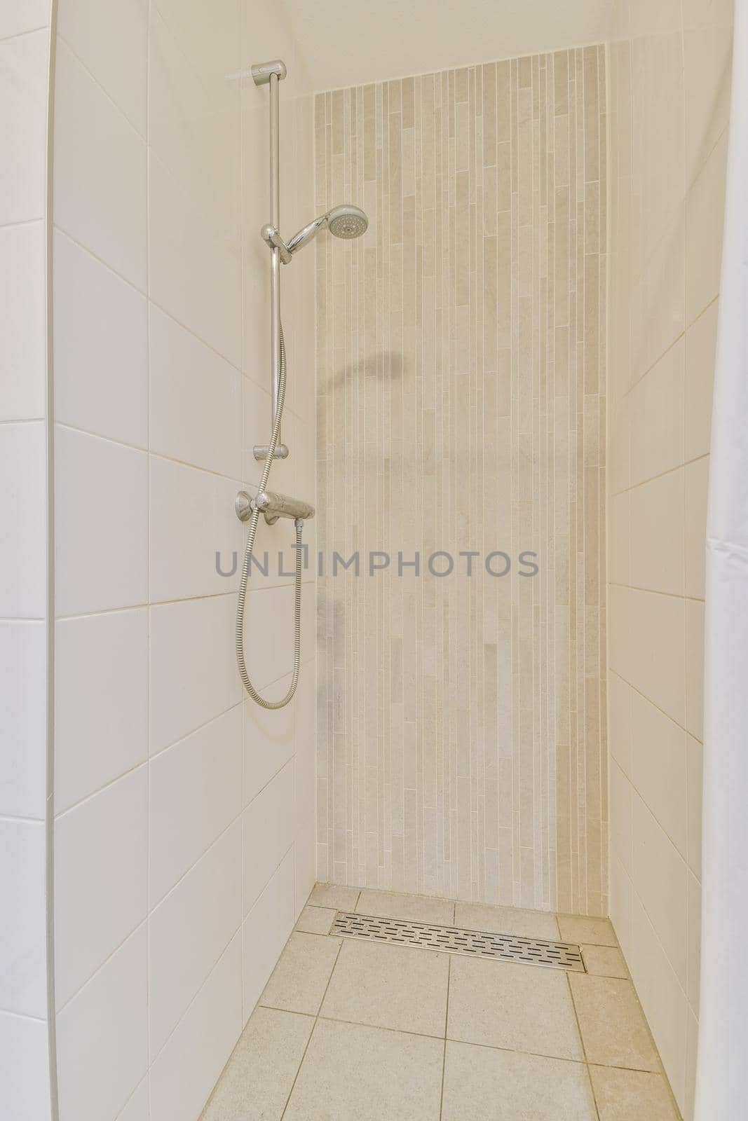 Bathroom interior finished with white tiles with a shower cabin in a modern house